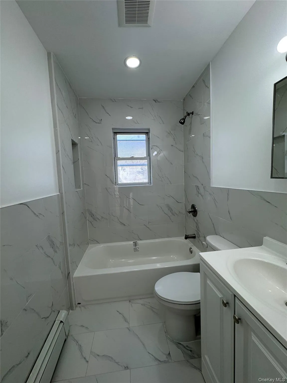 Bathroom with vanity, a combined bath / shower with marble appearance, a baseboard radiator, light marble finish flooring, and recessed lighting Bathroom with vanity, a combined bath / shower with marble appearance, a baseboard radiator, light marble finish flooring, and recessed lighting