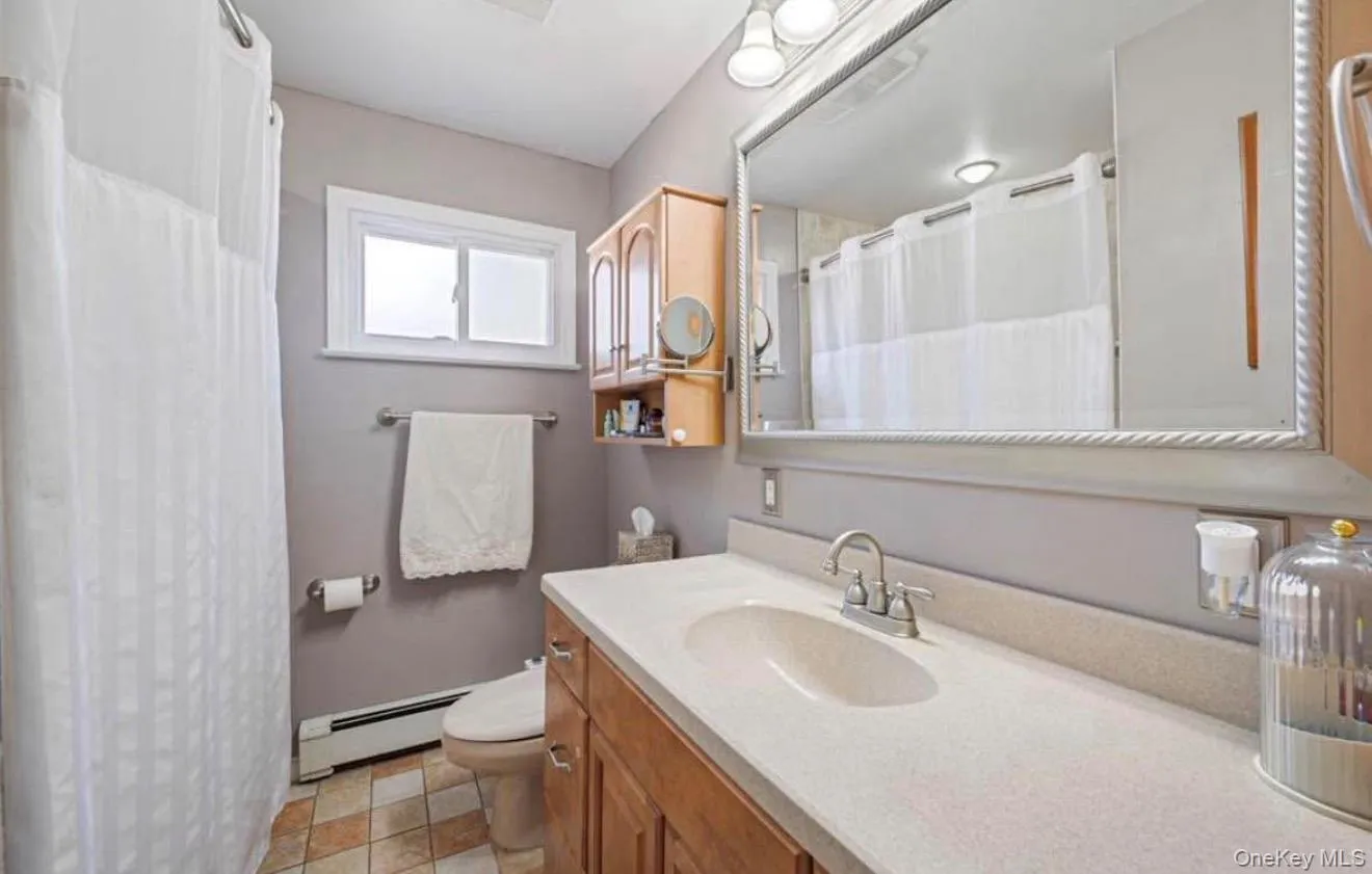 Full bathroom with vanity, a baseboard heating unit, and a shower with curtain Full bathroom with vanity, a baseboard heating unit, and a shower with curtain
