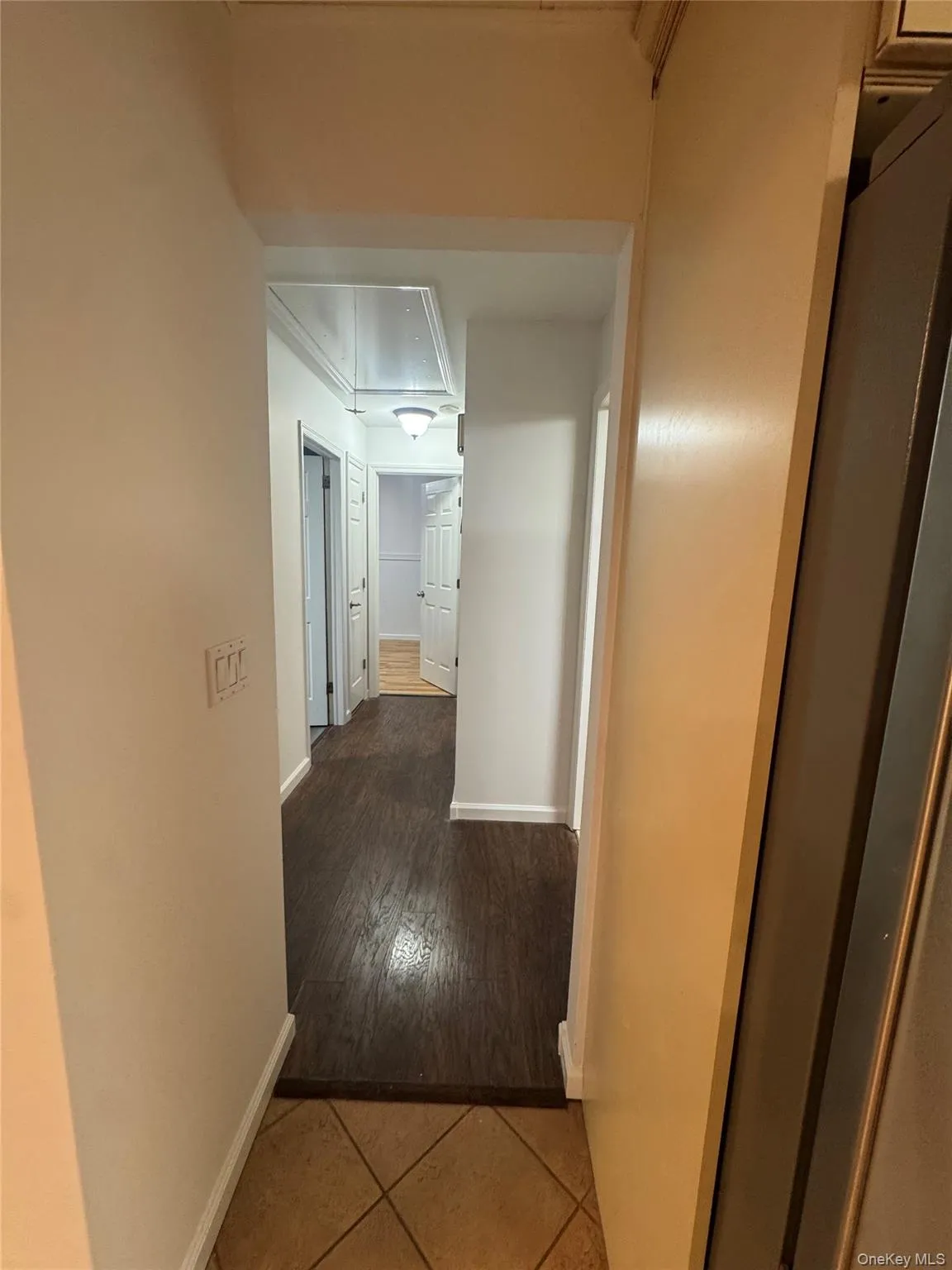 Hallway featuring dark tile patterned flooring and attic access Hallway featuring dark tile patterned flooring and attic access