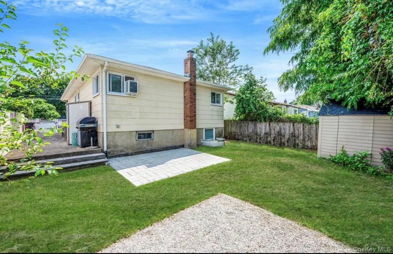 Rear view of property featuring a patio area, a fenced backyard, a chimney, and an outbuilding Rear view of property featuring a patio area, a fenced backyard, a chimney, and an outbuilding