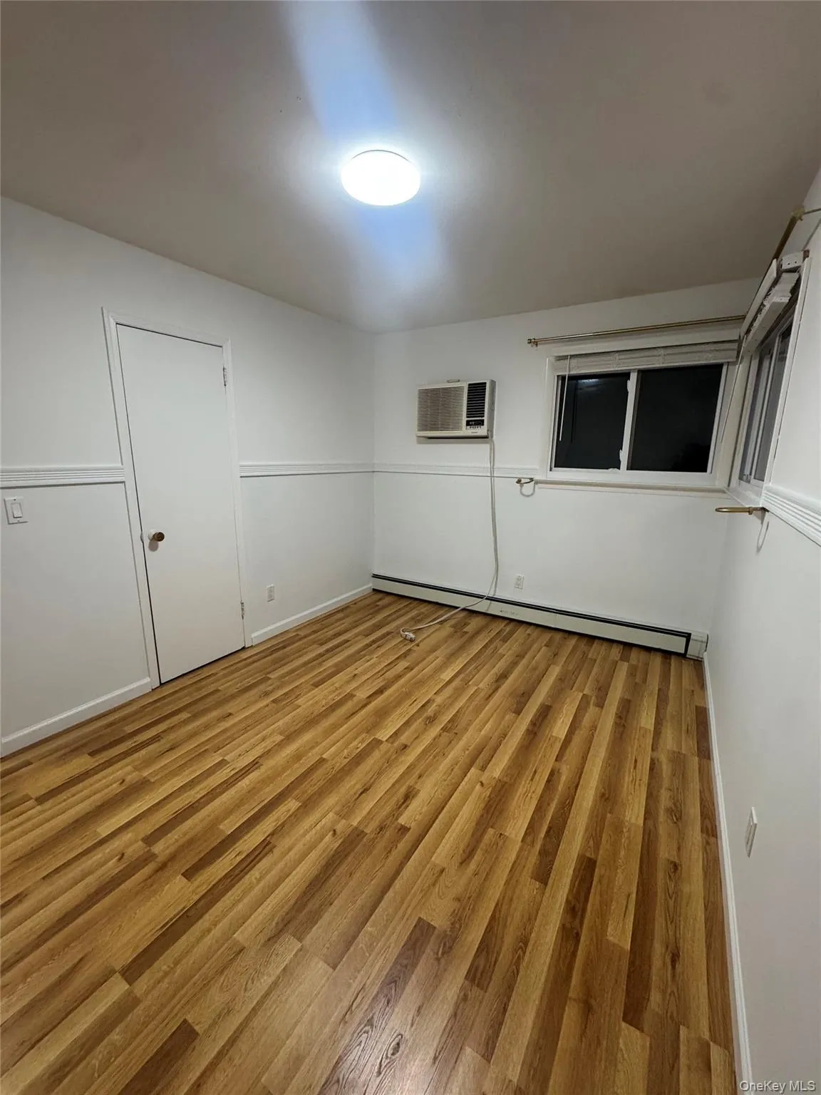 Empty room featuring light wood finished floors and a baseboard heating unit Empty room featuring light wood finished floors and a baseboard heating unit