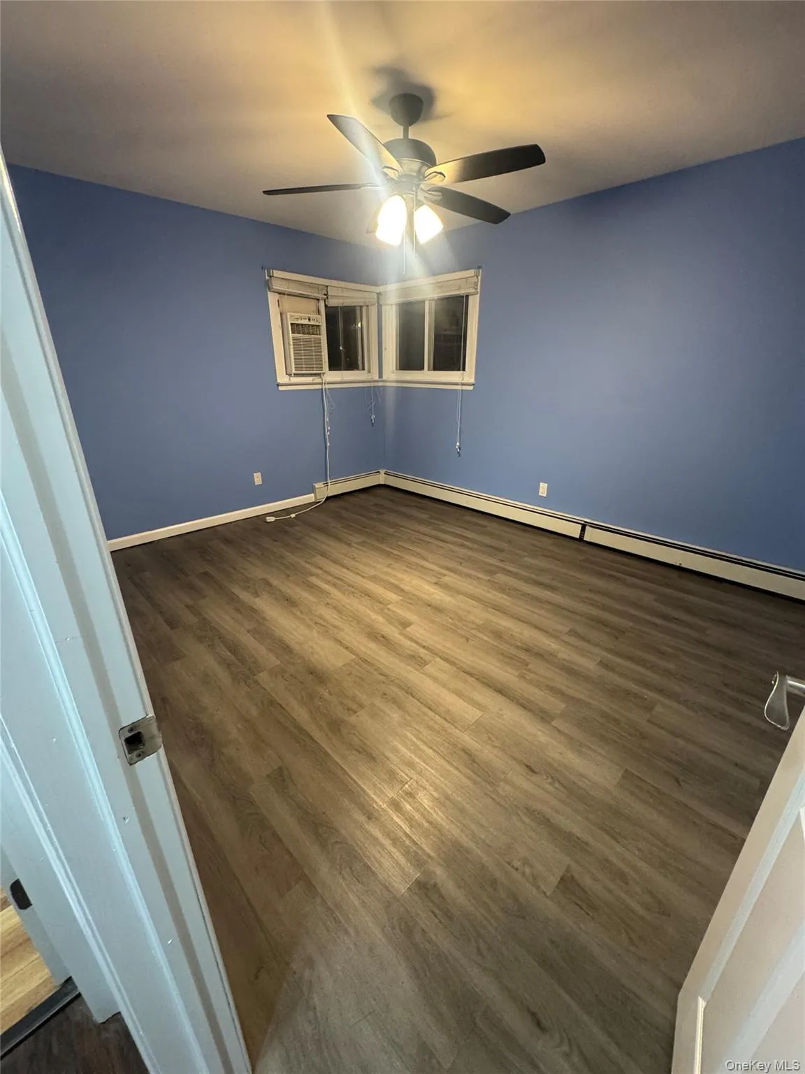 Spare room with dark wood-style floors, baseboard heating, and ceiling fan Spare room with dark wood-style floors, baseboard heating, and ceiling fan