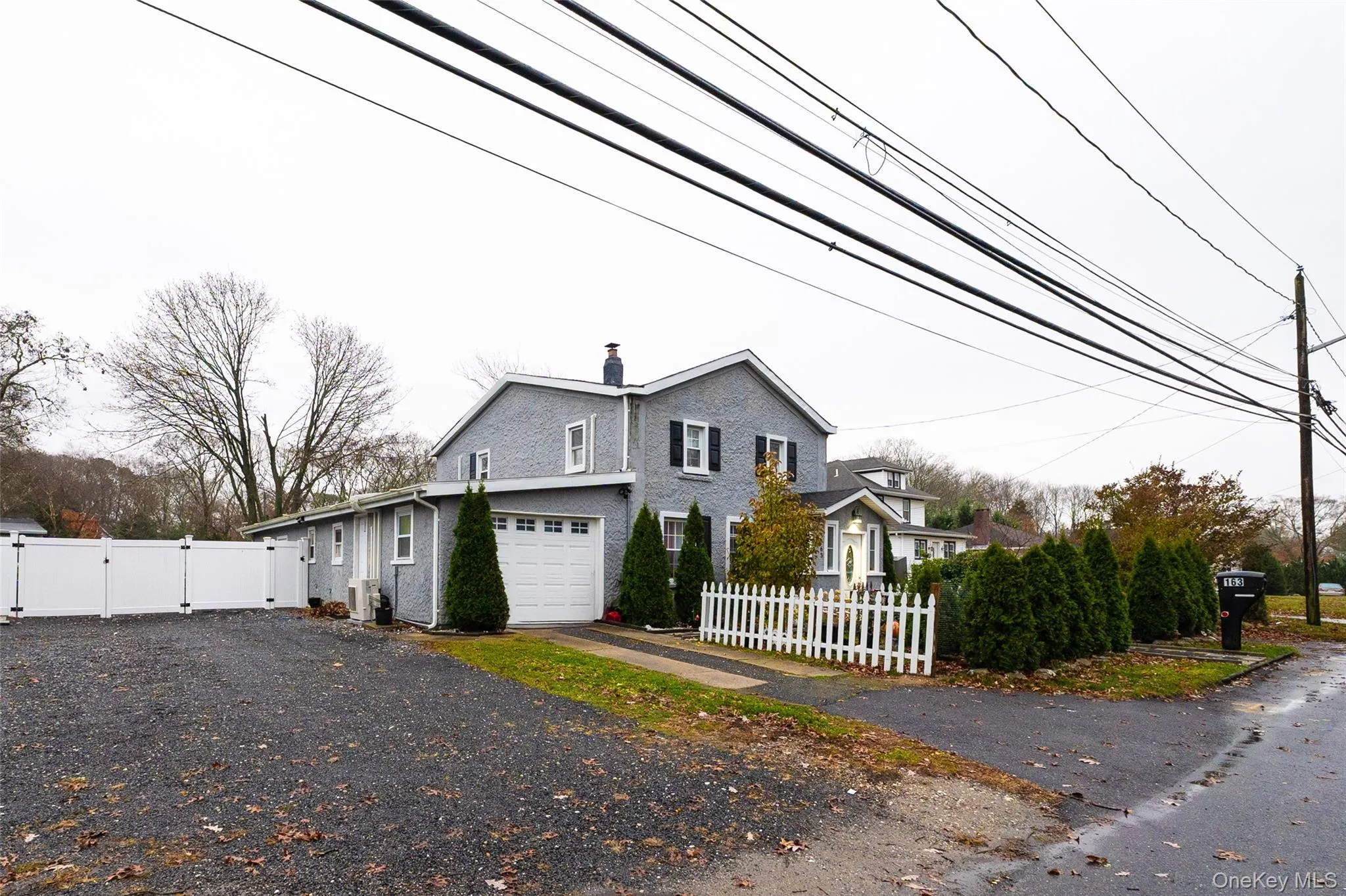 View of side of home featuring a gate, a chimney, driveway, and an attached garage View of side of home featuring a gate, a chimney, driveway, and an attached garage