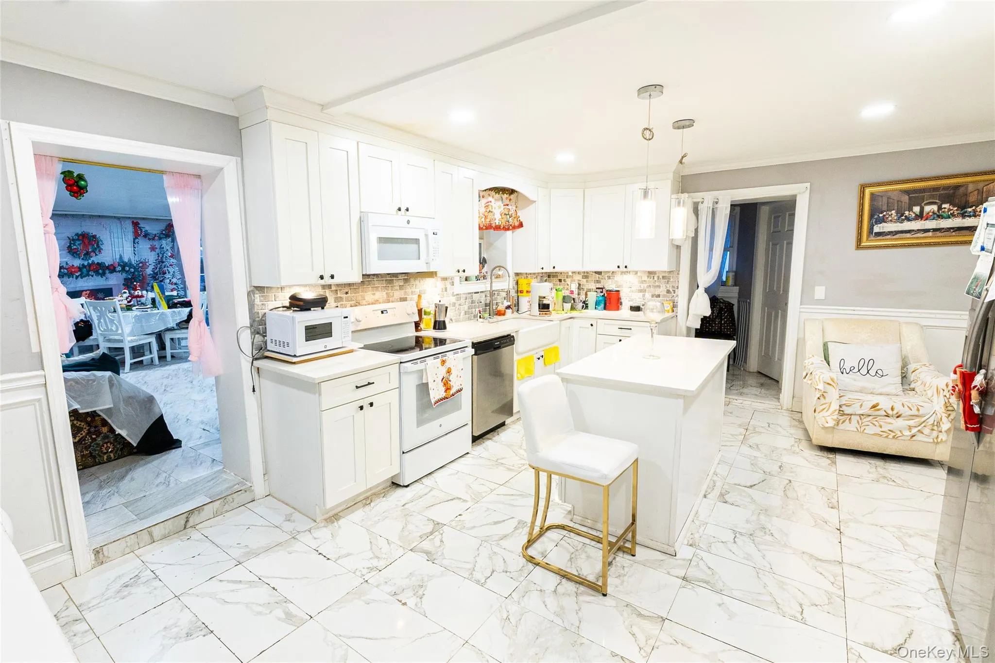 Kitchen featuring a wainscoted wall, crown molding, white appliances, white cabinetry, and light marble finish flooring Kitchen featuring a wainscoted wall, crown molding, white appliances, white cabinetry, and light marble finish flooring