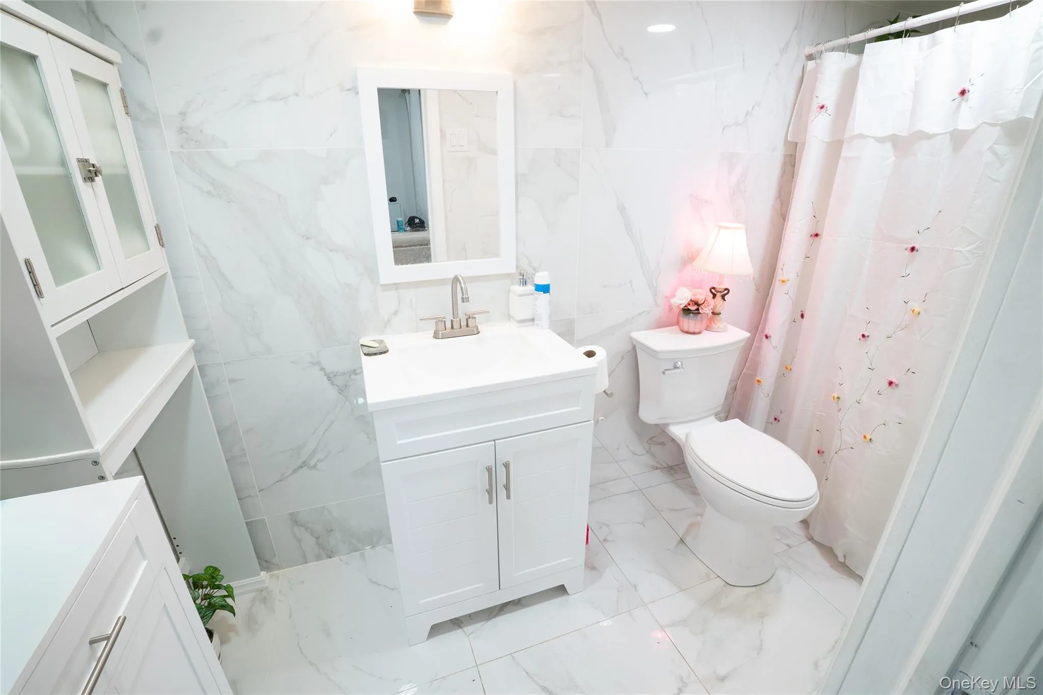 Bathroom featuring vanity, a shower with shower curtain, stone wall, light marble finish floors, and tile walls Bathroom featuring vanity, a shower with shower curtain, stone wall, light marble finish floors, and tile walls