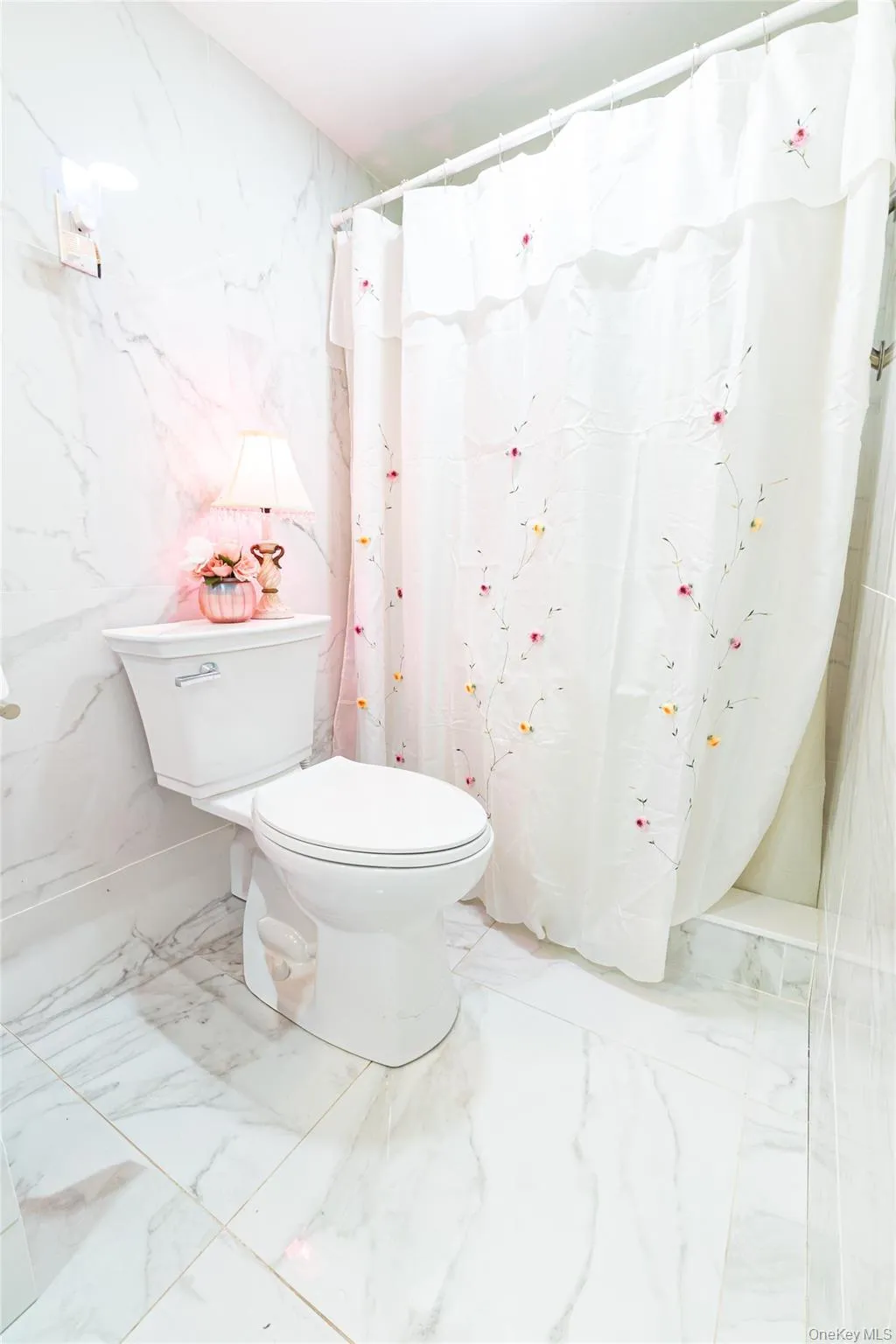 Bathroom with stone wall, marble tiled flooring, a shower with curtain, and tile walls Bathroom with stone wall, marble tiled flooring, a shower with curtain, and tile walls