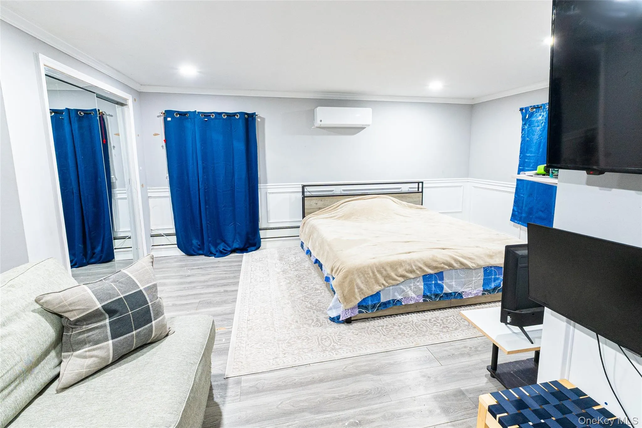 Bedroom featuring ornamental molding, light wood-type flooring, wainscoting, a decorative wall, and recessed lighting Bedroom featuring ornamental molding, light wood-type flooring, wainscoting, a decorative wall, and recessed lighting