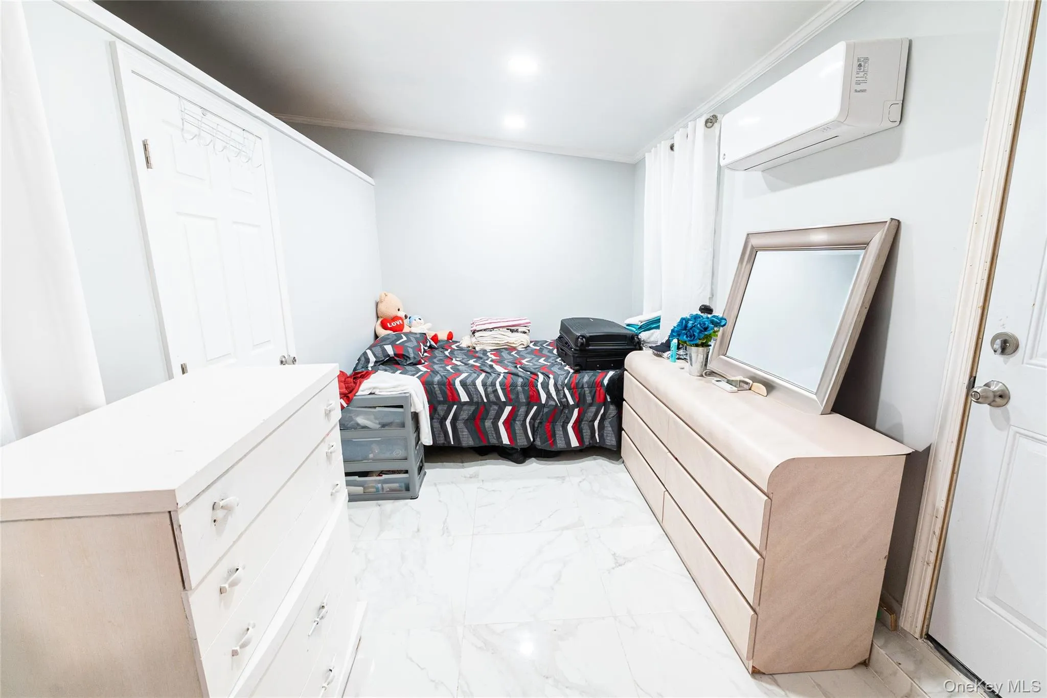 Bedroom with light marble finish flooring and an AC wall unit Bedroom with light marble finish flooring and an AC wall unit