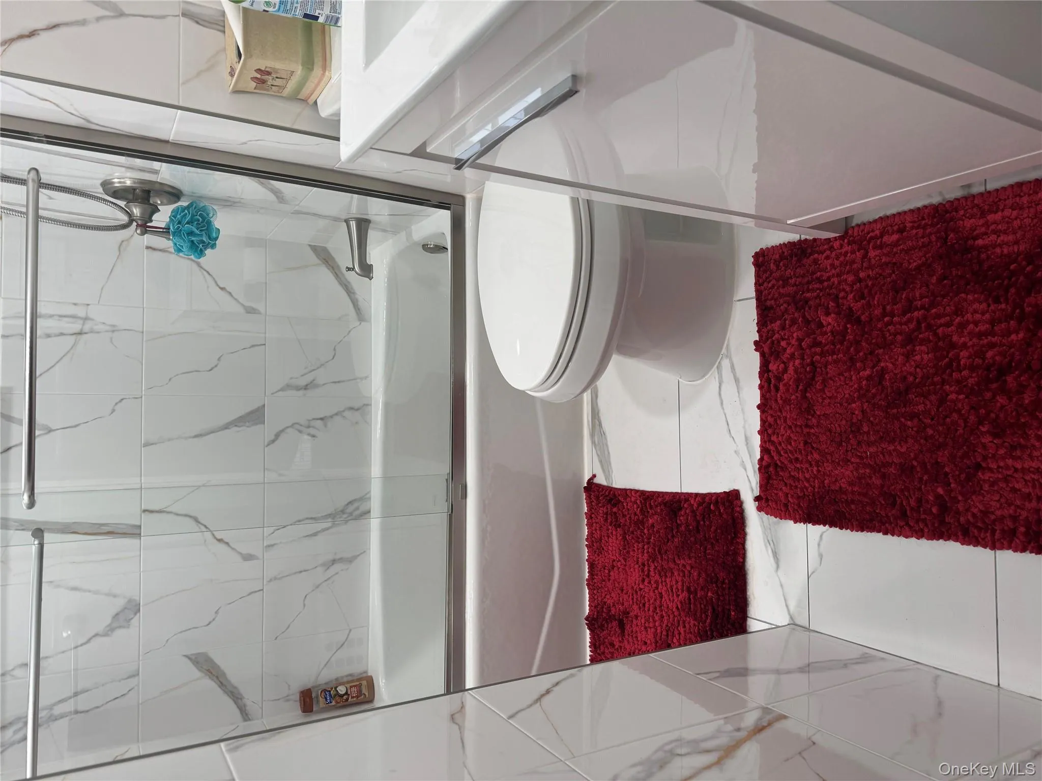 Full bathroom featuring marble look tile flooring, combined bath / shower with glass door, and vanity Full bathroom featuring marble look tile flooring, combined bath / shower with glass door, and vanity