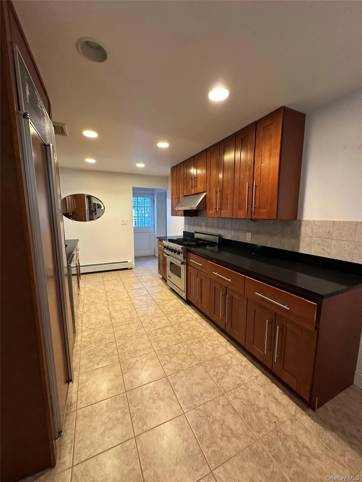 Kitchen with decorative backsplash, designer range, recessed lighting, light tile patterned floors, and under cabinet range hood Kitchen with decorative backsplash, designer range, recessed lighting, light tile patterned floors, and under cabinet range hood