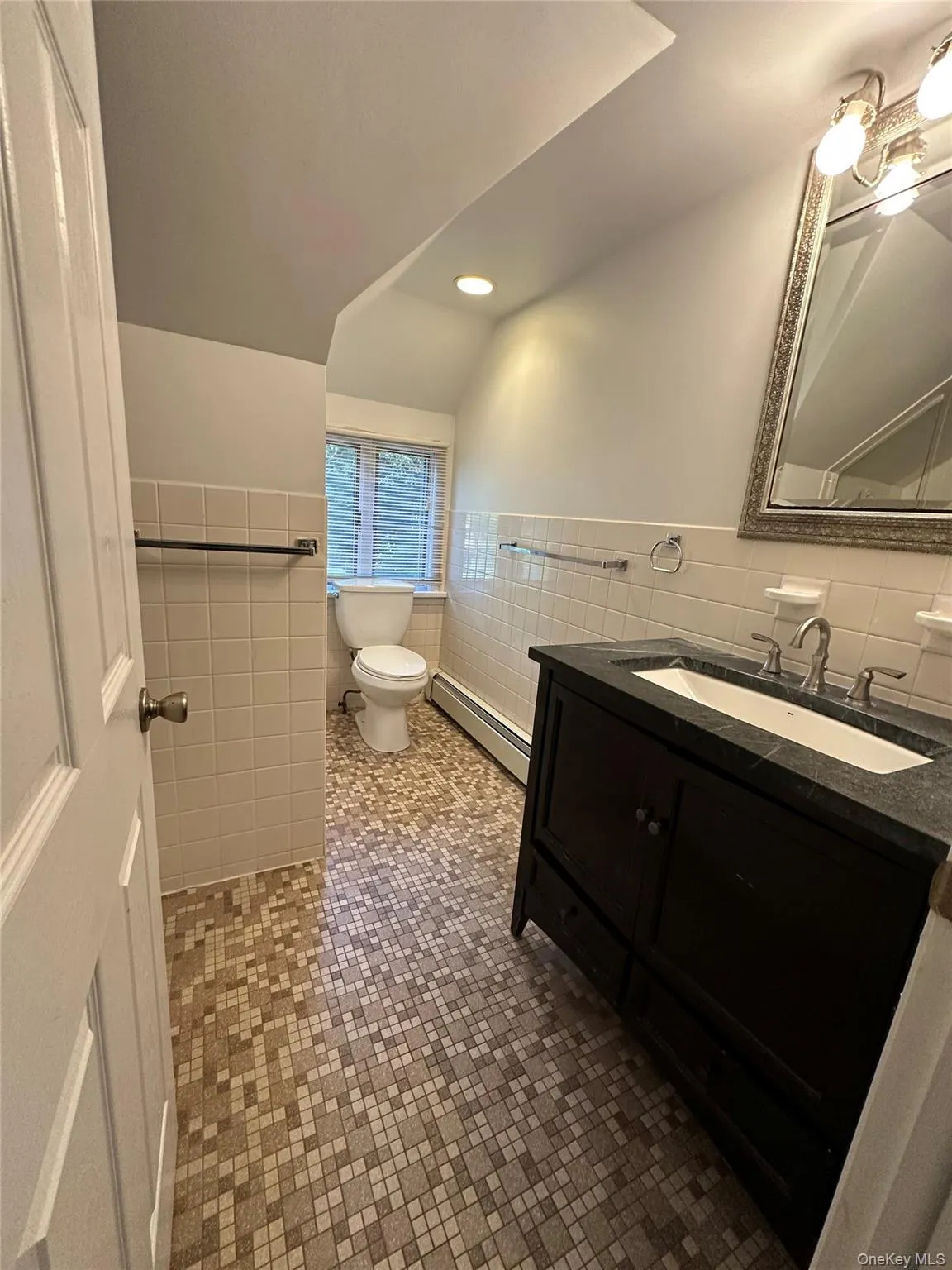 Full bath featuring tile walls, a wainscoted wall, vanity, baseboard heating, and recessed lighting Full bath featuring tile walls, a wainscoted wall, vanity, baseboard heating, and recessed lighting