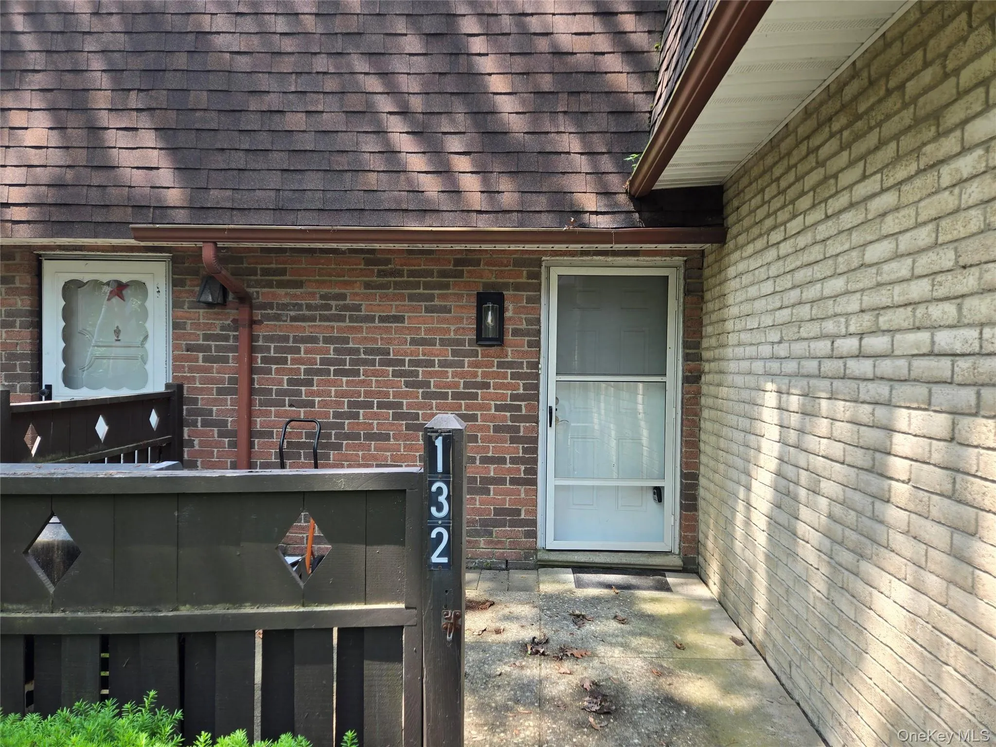 View of exterior entry featuring brick siding and a shingled roof View of exterior entry featuring brick siding and a shingled roof