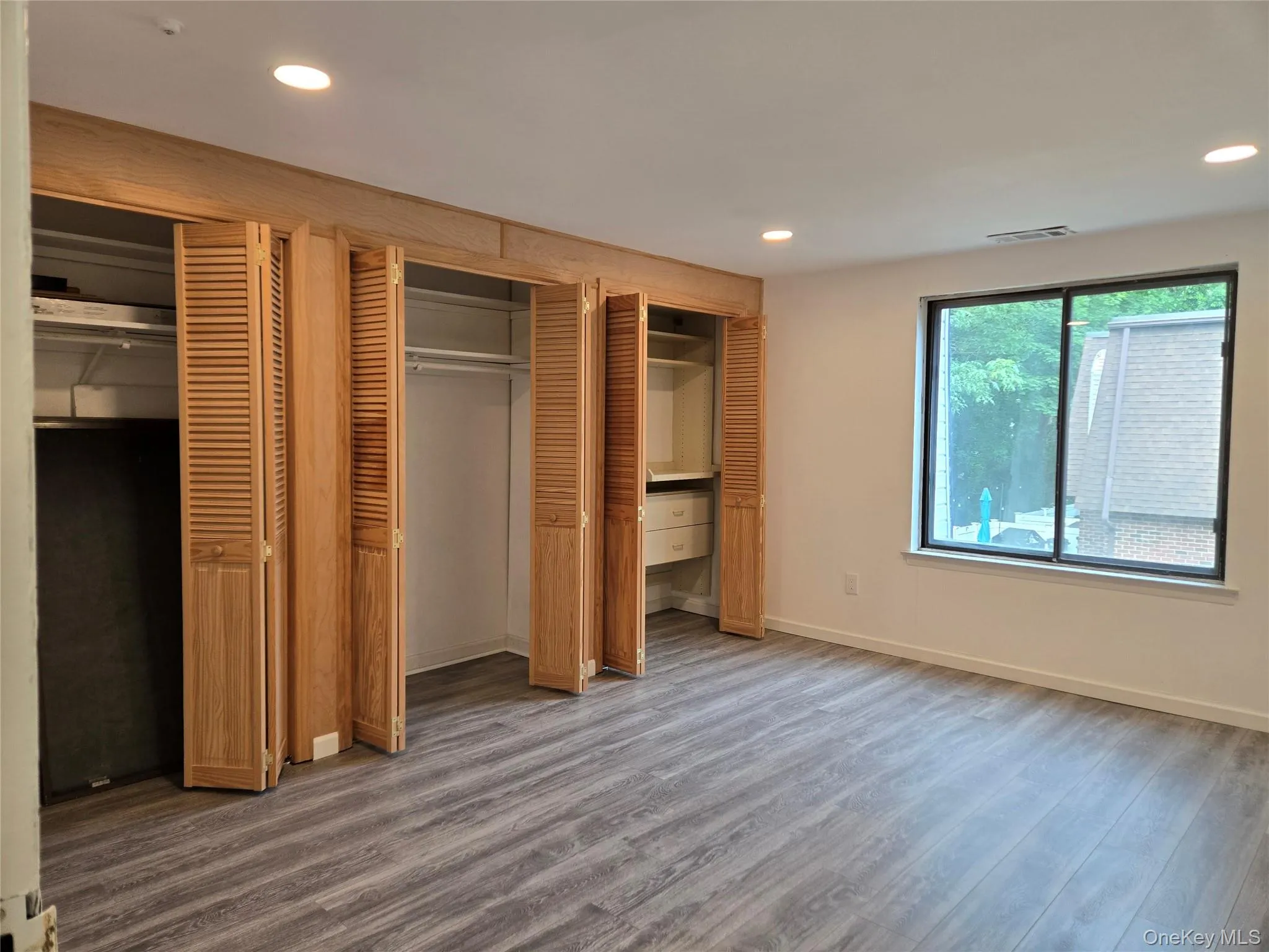 Unfurnished bedroom with two closets, recessed lighting, and wood finished floors Unfurnished bedroom with two closets, recessed lighting, and wood finished floors