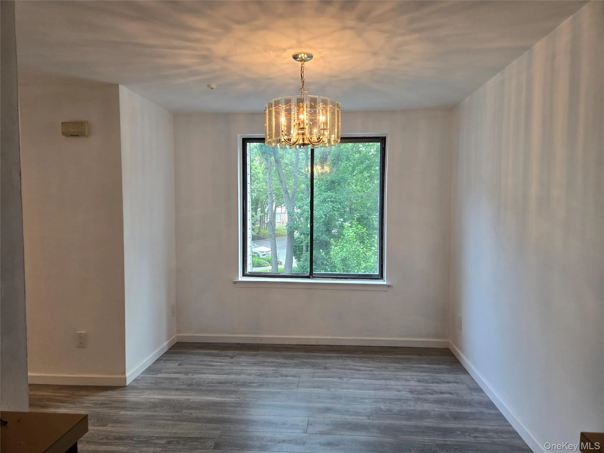 Unfurnished dining area with dark wood-type flooring and a chandelier Unfurnished dining area with dark wood-type flooring and a chandelier