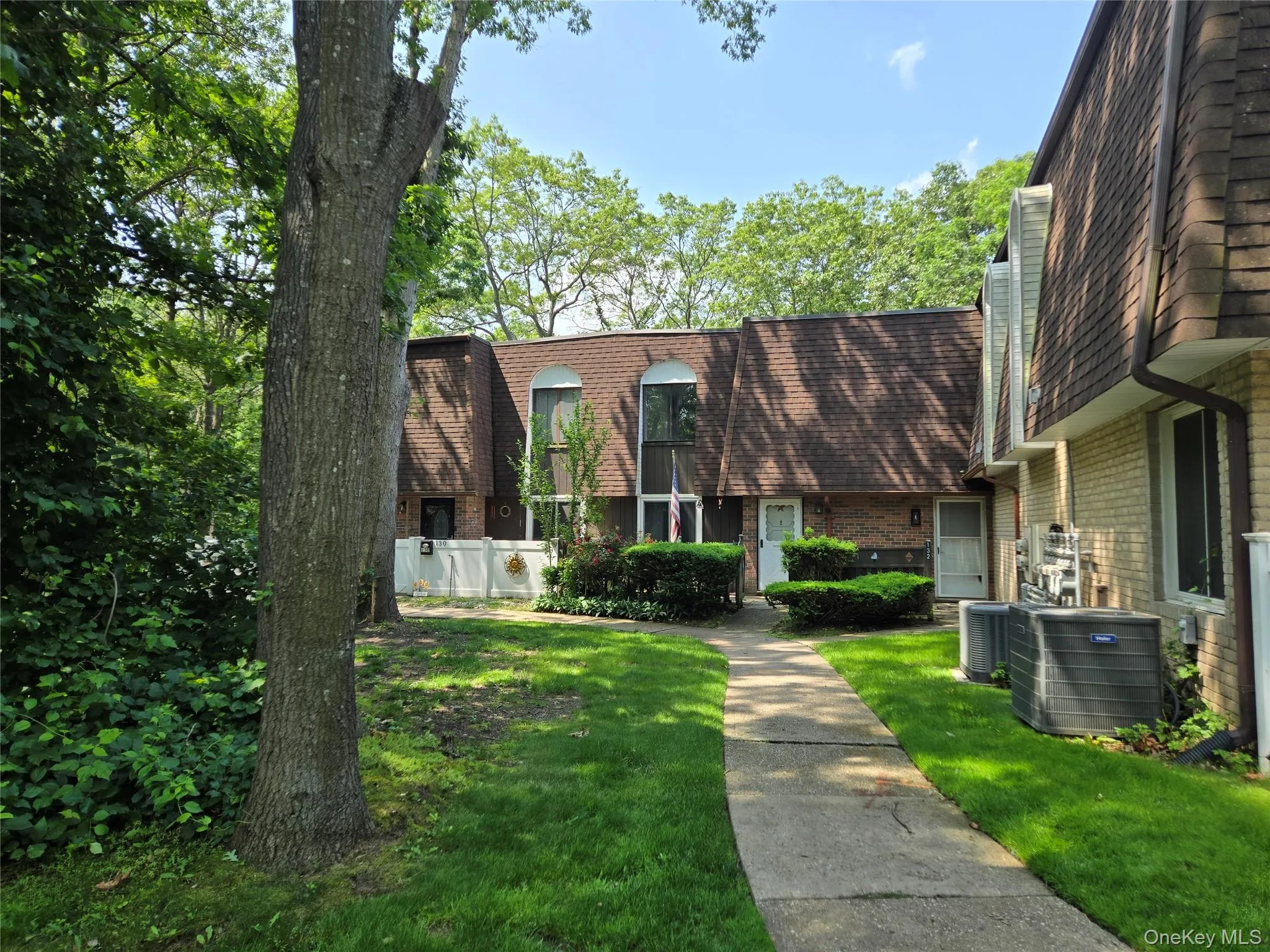 View of front of home featuring brick siding, a front lawn, a shingled roof, and mansard roof View of front of home featuring brick siding, a front lawn, a shingled roof, and mansard roof