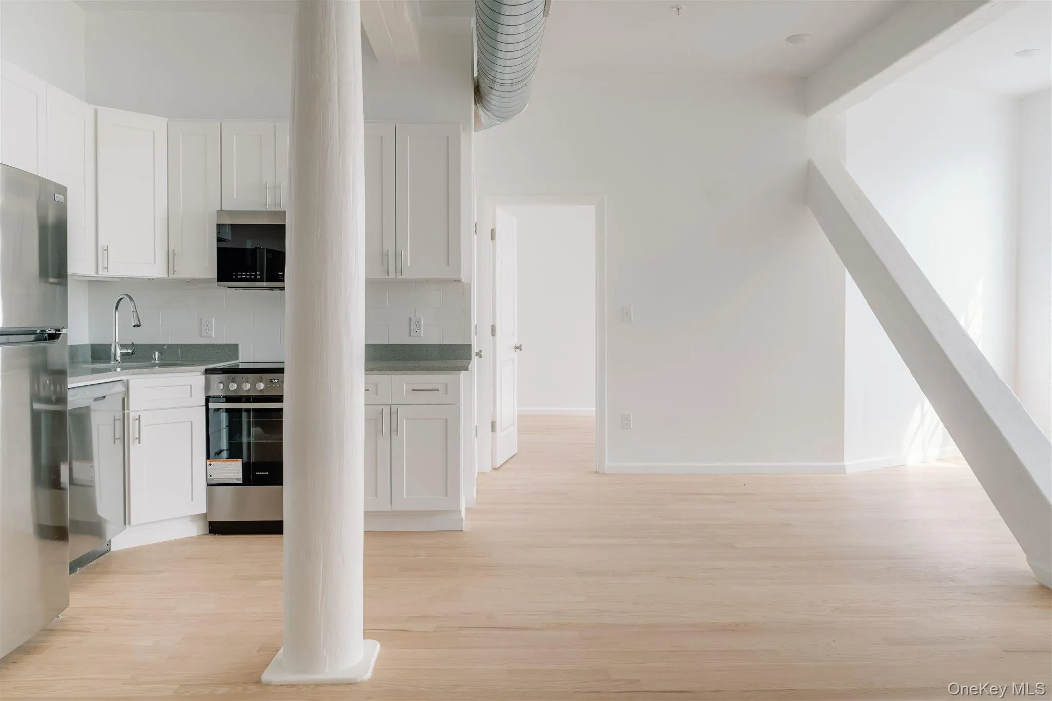 Kitchen with white cabinetry, stainless steel appliances, light wood finished floors, and decorative backsplash Kitchen with white cabinetry, stainless steel appliances, light wood finished floors, and decorative backsplash