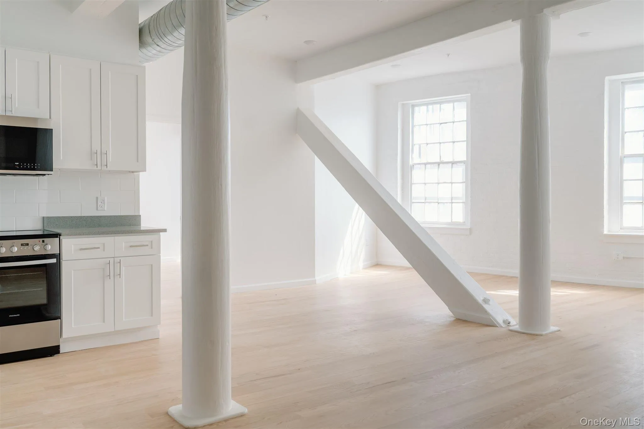 Kitchen with white cabinets, stainless steel appliances, and light wood finished floors Kitchen with white cabinets, stainless steel appliances, and light wood finished floors