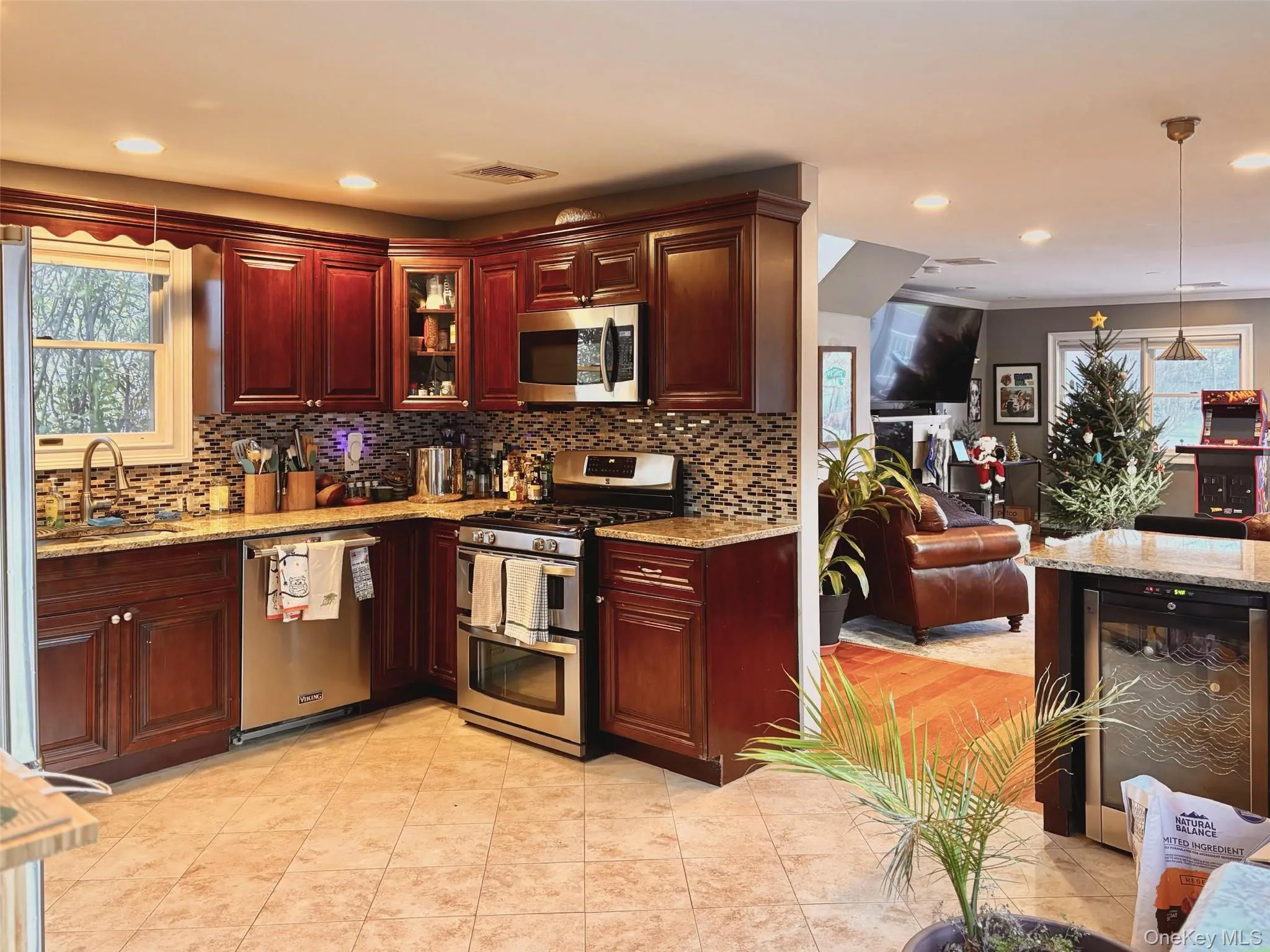 Kitchen featuring stainless steel appliances, light stone counters, glass insert cabinets, decorative light fixtures, and open floor plan Kitchen featuring stainless steel appliances, light stone counters, glass insert cabinets, decorative light fixtures, and open floor plan