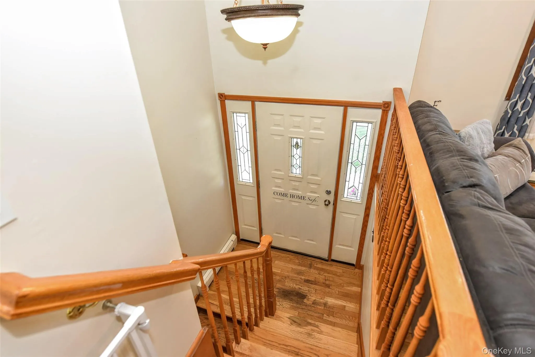 Foyer entry featuring wood-finish flooring, a white paneled door with decorative glass inserts, and 2 sidelights Foyer entry featuring wood-finish flooring, a white paneled door with decorative glass inserts, and 2 sidelights