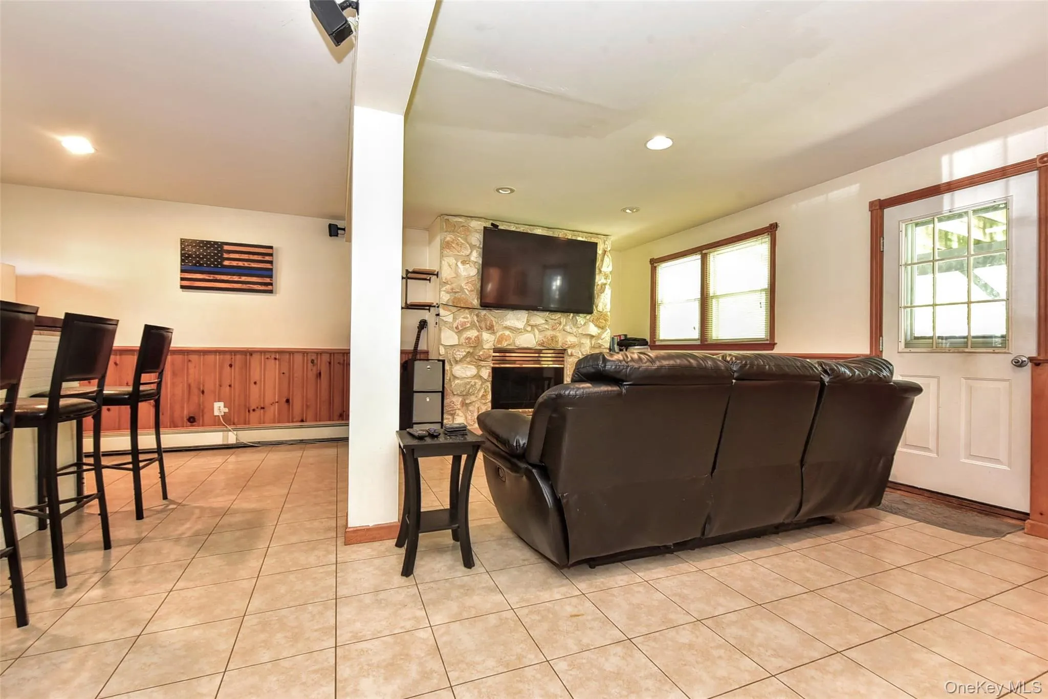 Living area showcasing light-toned tile flooring and a separate entrance to the backyard Living area showcasing light-toned tile flooring and a separate entrance to the backyard