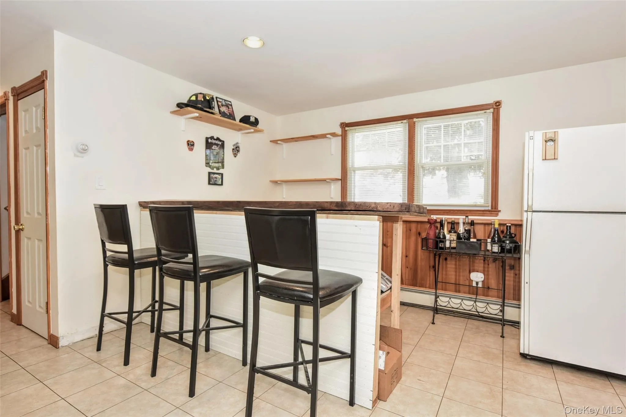 Built-in bar area with a wood-finish countertop, shiplap paneling, natural wood paneling, and ceramic tile flooring Built-in bar area with a wood-finish countertop, shiplap paneling, natural wood paneling, and ceramic tile flooring