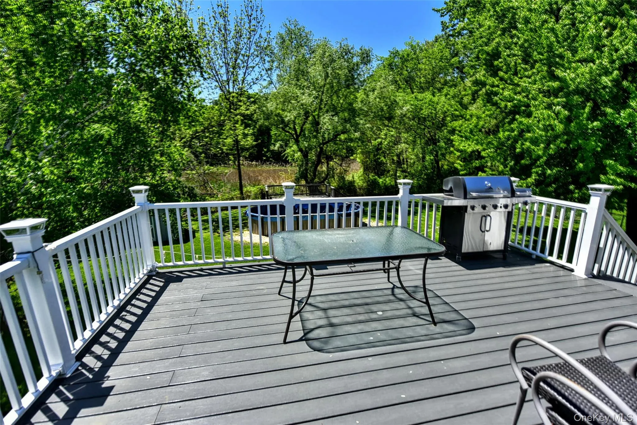 Spacious composite deck with white railings and integrated post lighting Spacious composite deck with white railings and integrated post lighting