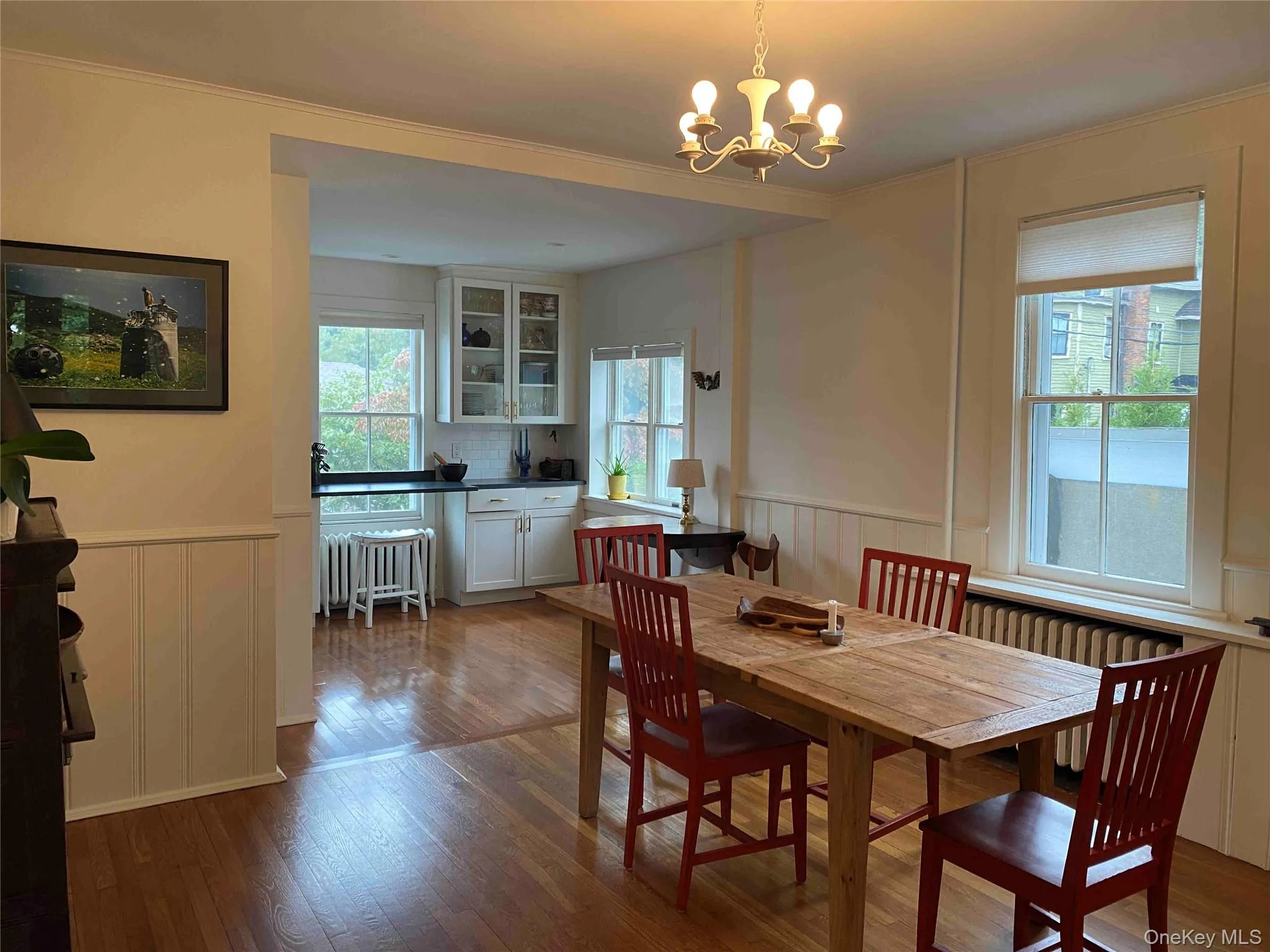 Dining space featuring wainscoting, a decorative wall, crown molding, dark wood-type flooring, and radiator Dining space featuring wainscoting, a decorative wall, crown molding, dark wood-type flooring, and radiator