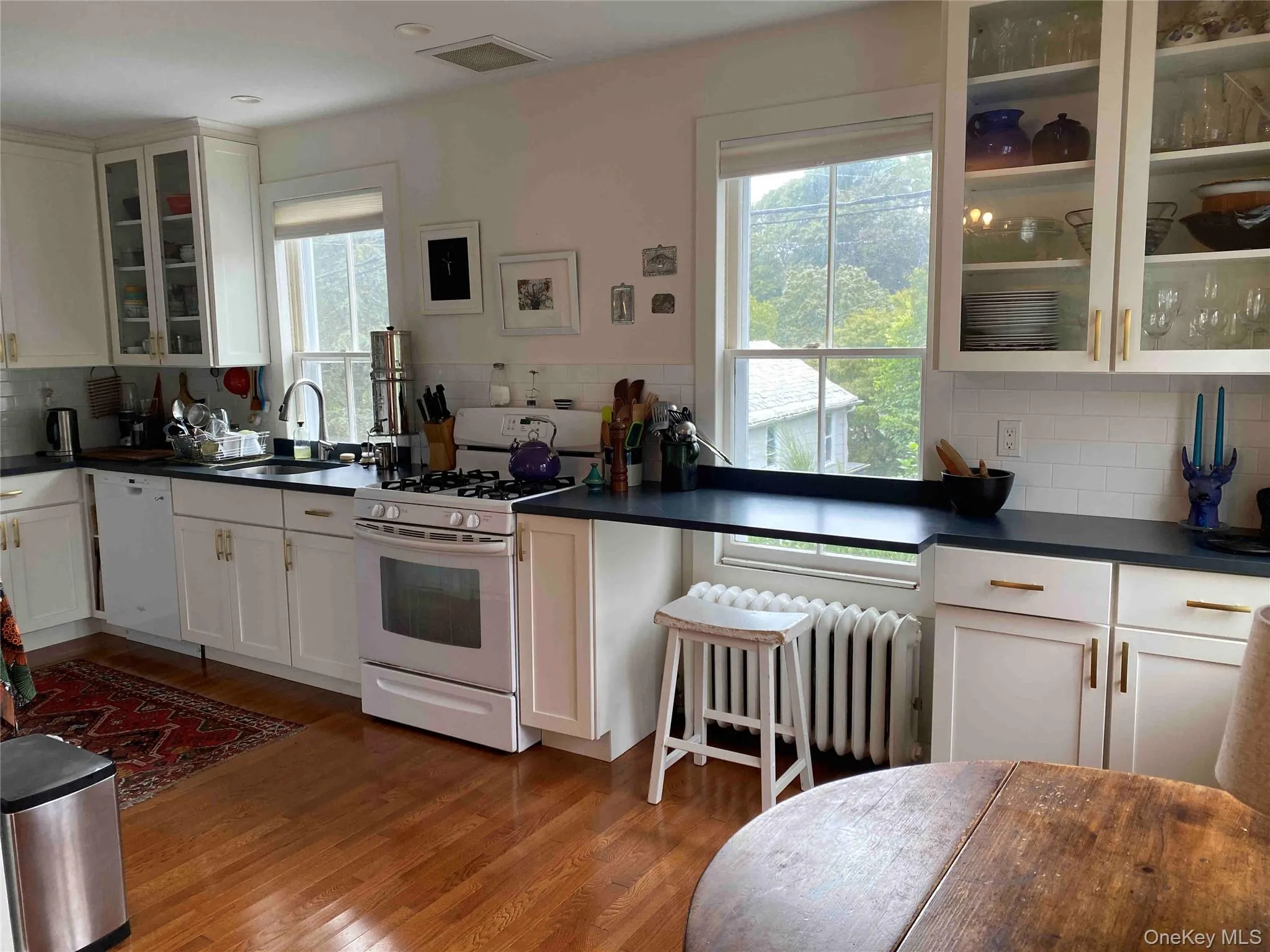 Kitchen featuring glass insert cabinets, tasteful backsplash, white appliances, and white cabinetry Kitchen featuring glass insert cabinets, tasteful backsplash, white appliances, and white cabinetry