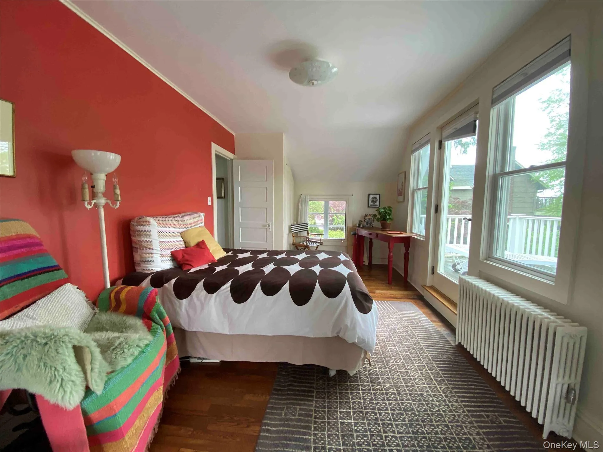 Bedroom featuring radiator, dark wood-type flooring, access to exterior, and vaulted ceiling Bedroom featuring radiator, dark wood-type flooring, access to exterior, and vaulted ceiling