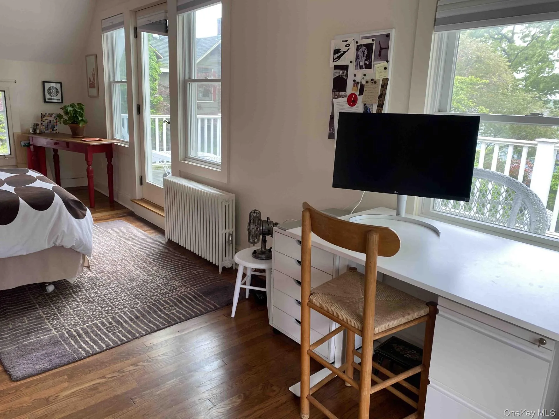 Bedroom featuring hardwood / wood-style floors, radiator, lofted ceiling, and access to exterior Bedroom featuring hardwood / wood-style floors, radiator, lofted ceiling, and access to exterior