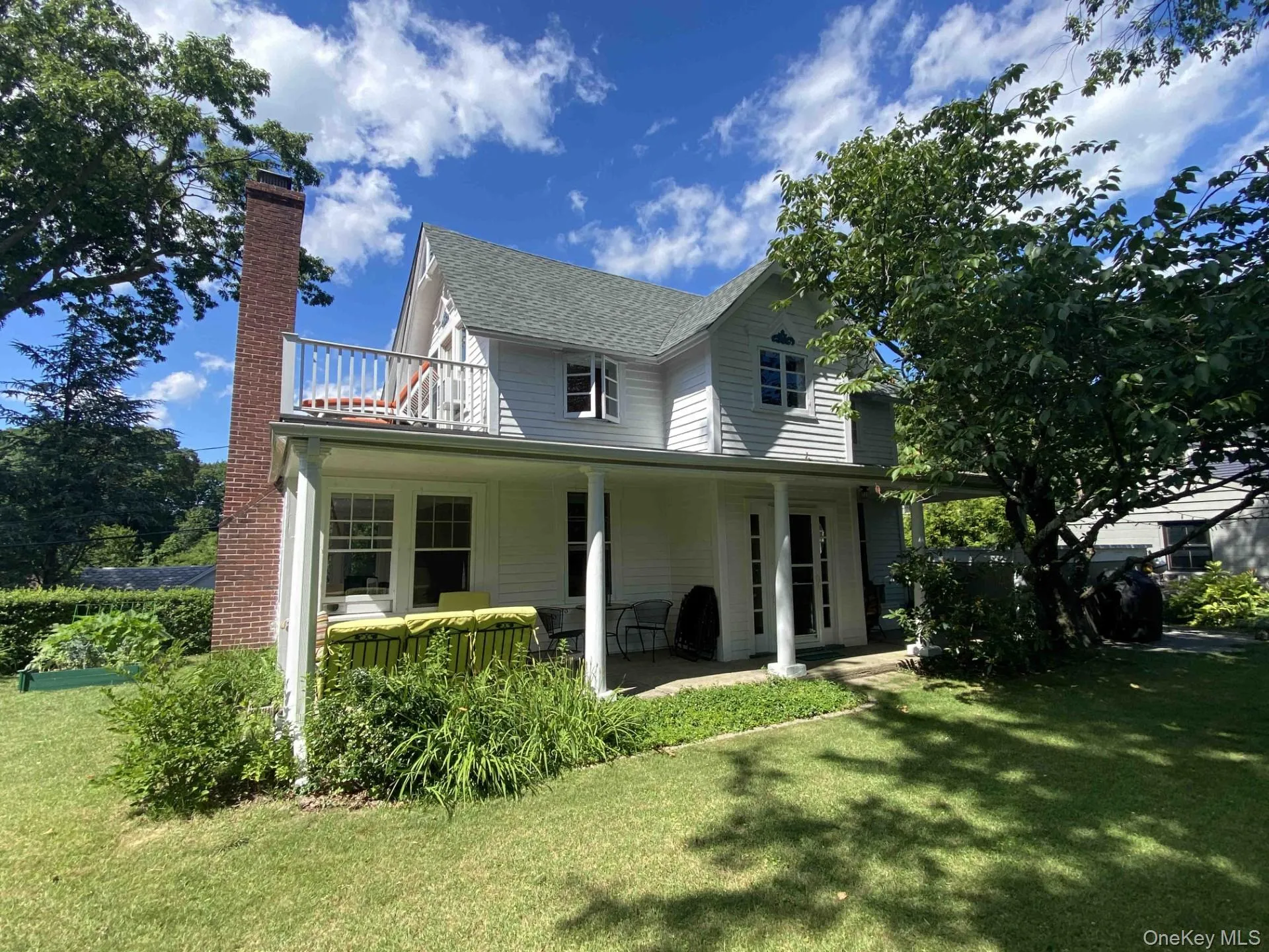 Rear view of property featuring a yard, a patio area, a chimney, and a balcony Rear view of property featuring a yard, a patio area, a chimney, and a balcony