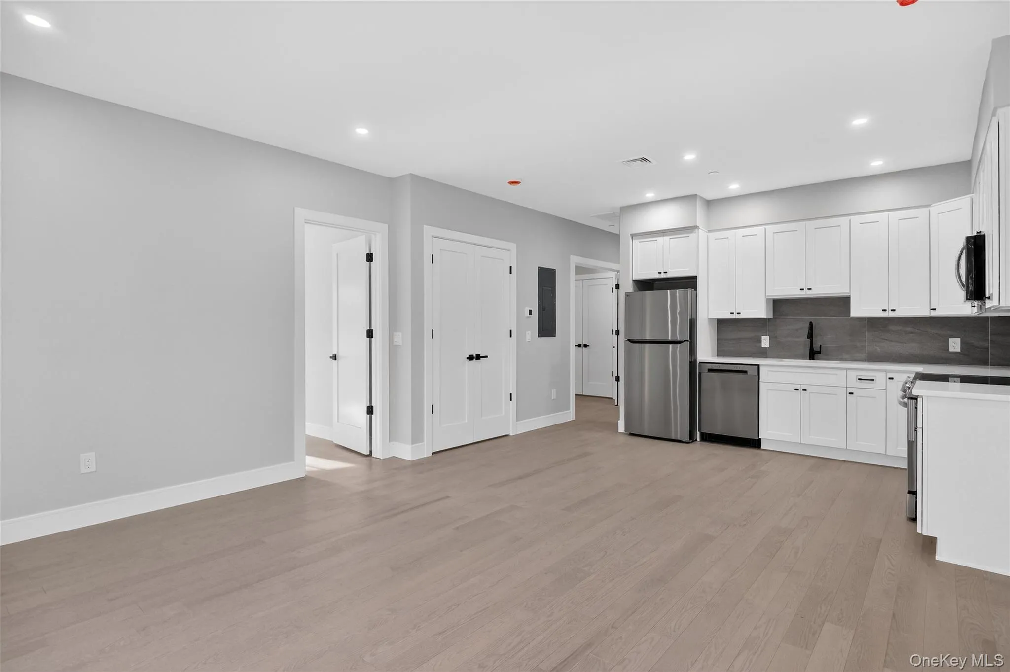 Kitchen featuring white cabinets, decorative backsplash, stainless steel appliances, light wood-style floors, and recessed lighting Kitchen featuring white cabinets, decorative backsplash, stainless steel appliances, light wood-style floors, and recessed lighting