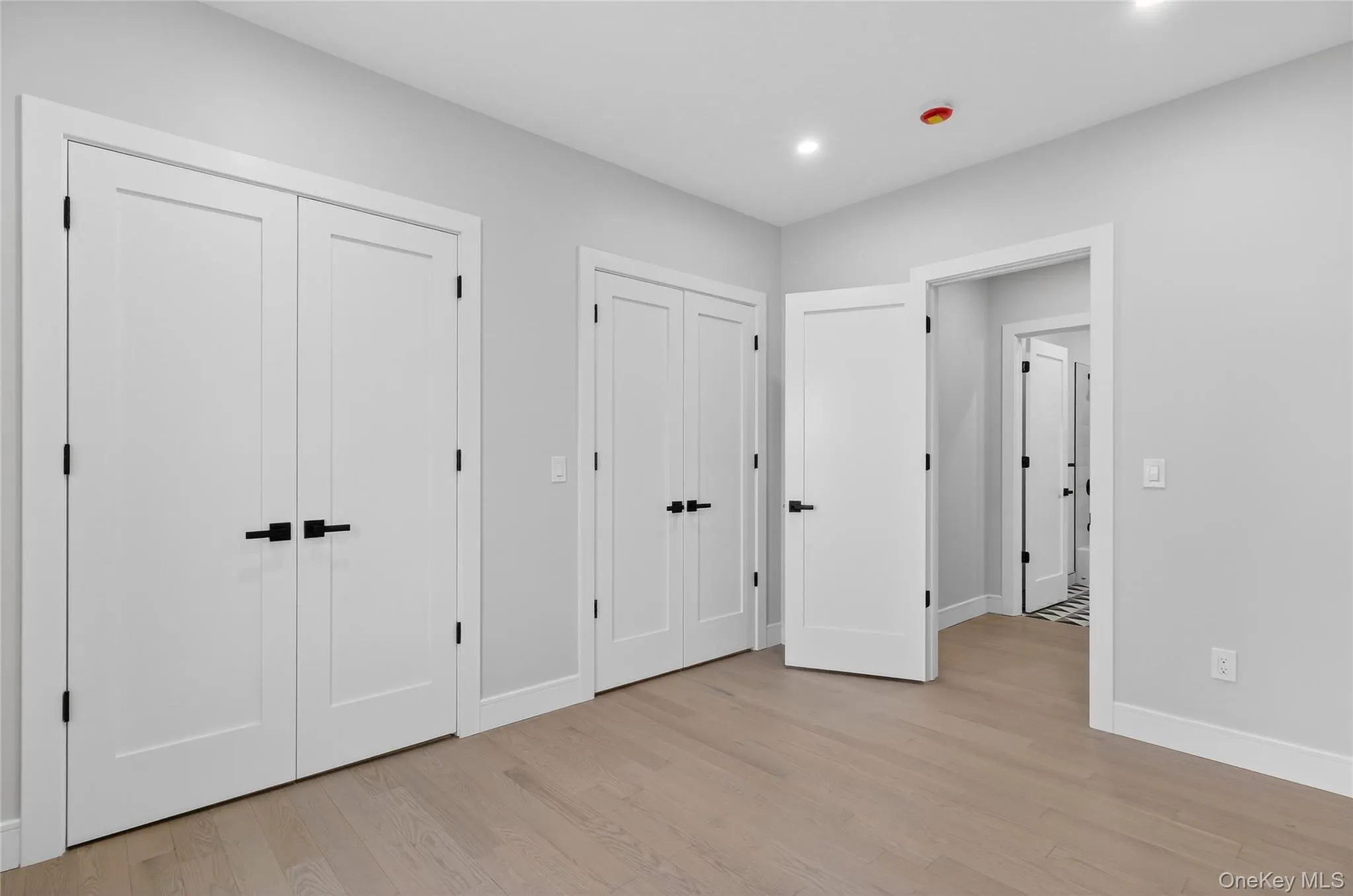 Unfurnished bedroom with multiple closets, light wood-type flooring, and recessed lighting Unfurnished bedroom with multiple closets, light wood-type flooring, and recessed lighting