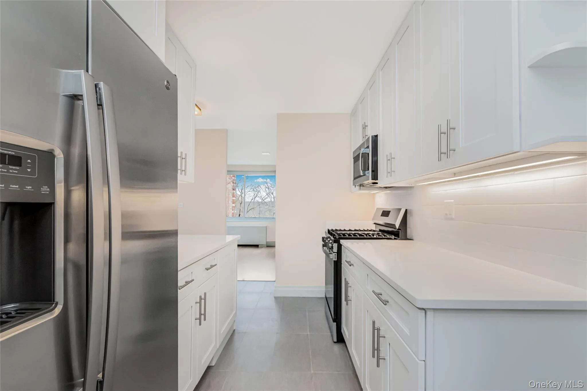 Kitchen with stainless steel appliances, white cabinetry, and light stone countertops Kitchen with stainless steel appliances, white cabinetry, and light stone countertops