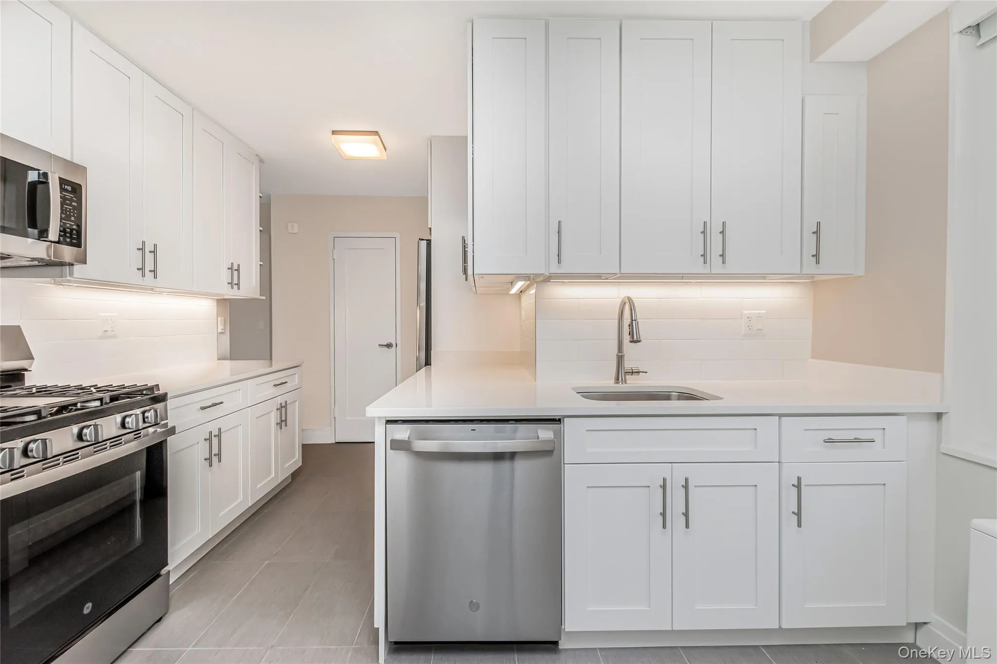Kitchen featuring stainless steel appliances, tasteful backsplash, and white cabinetry Kitchen featuring stainless steel appliances, tasteful backsplash, and white cabinetry