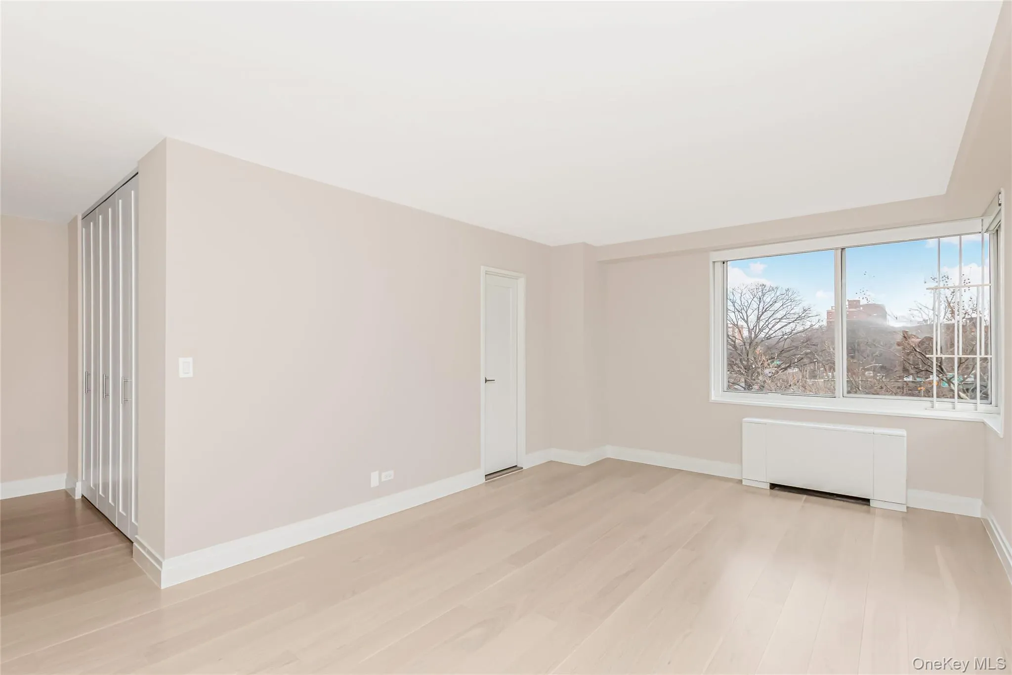 Unfurnished room with radiator heating unit and light wood-style flooring Unfurnished room with radiator heating unit and light wood-style flooring
