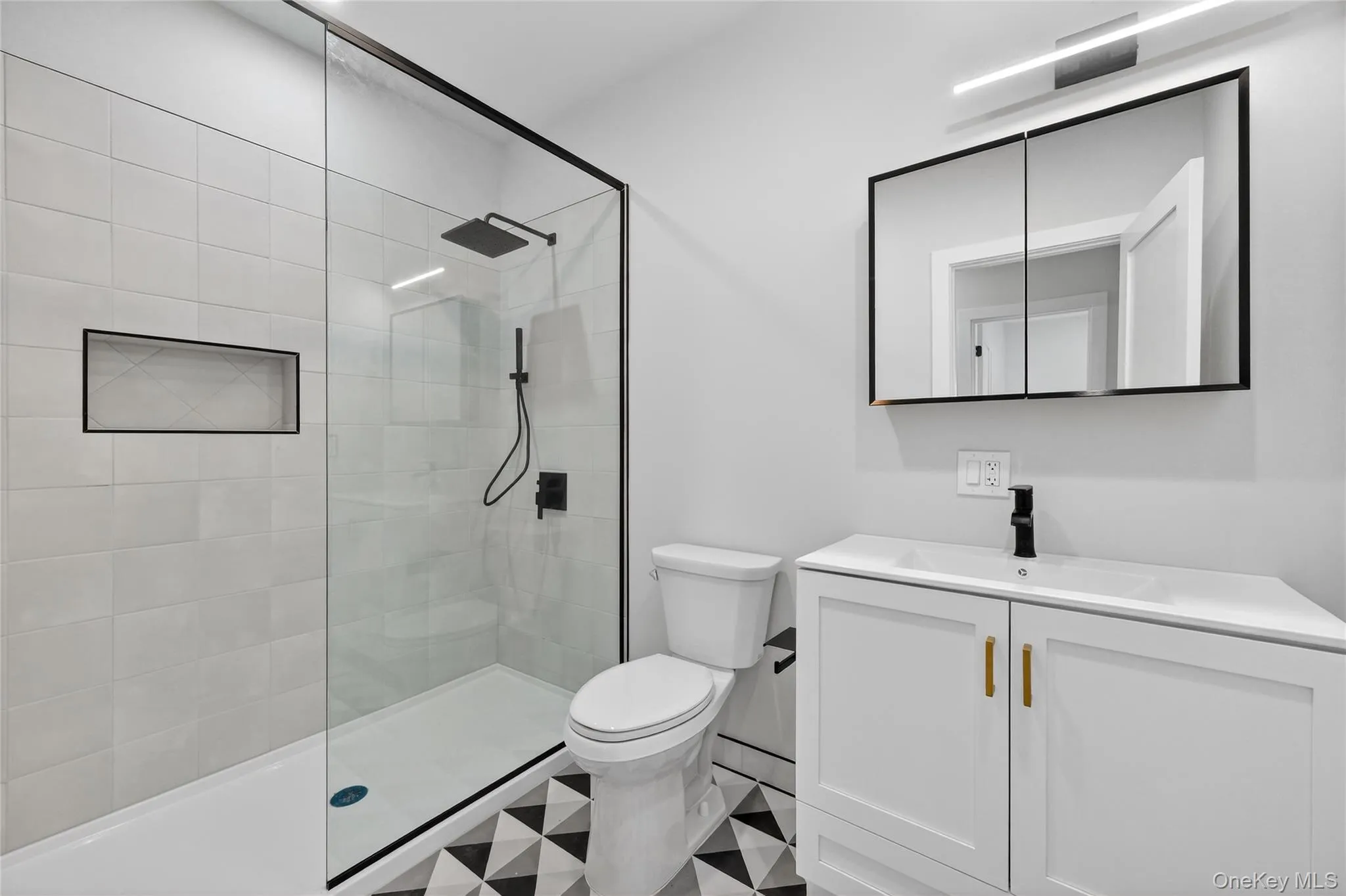 Bathroom featuring tiled shower, vanity, and tile patterned floors Bathroom featuring tiled shower, vanity, and tile patterned floors