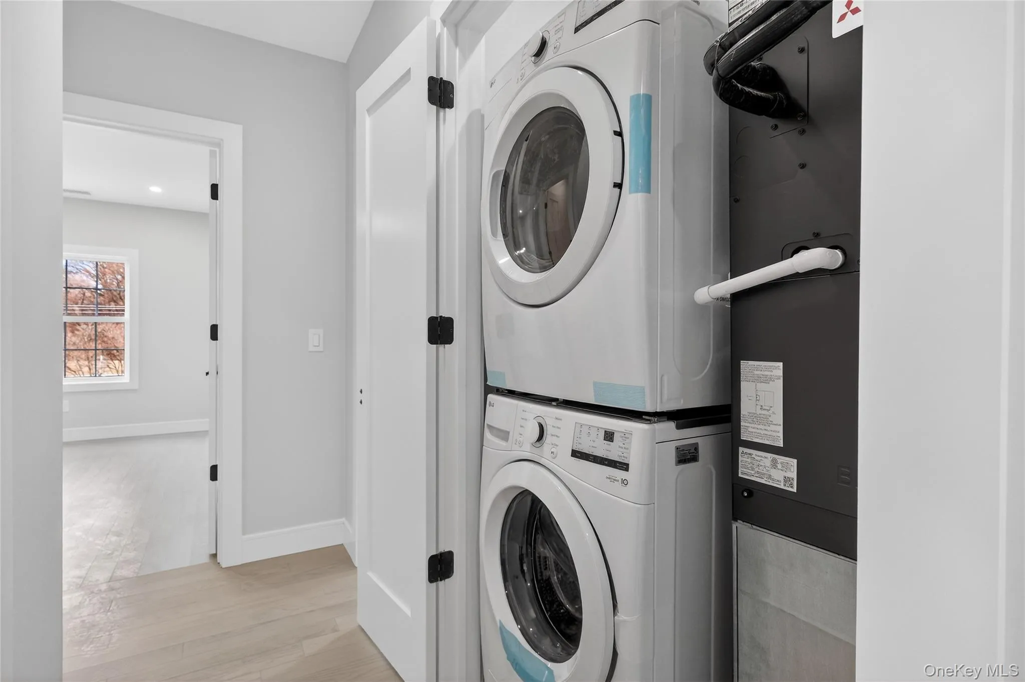 Washroom with stacked washer / drying machine, light wood-style floors, heating unit, and recessed lighting Washroom with stacked washer / drying machine, light wood-style floors, heating unit, and recessed lighting