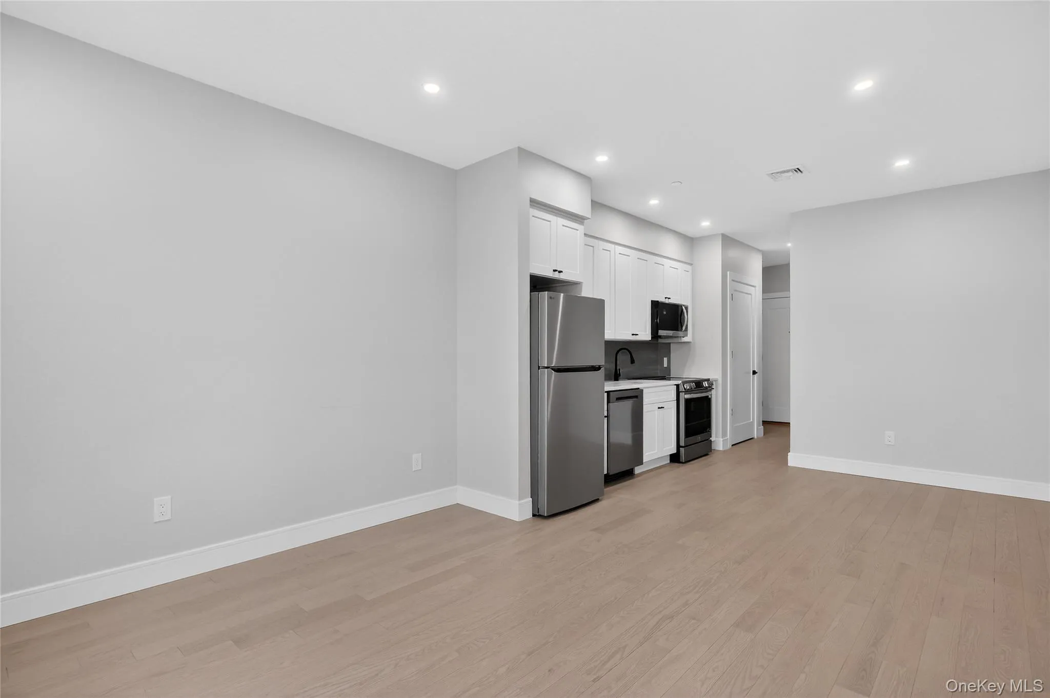 Kitchen featuring white cabinets, appliances with stainless steel finishes, light wood-style floors, light countertops, and recessed lighting Kitchen featuring white cabinets, appliances with stainless steel finishes, light wood-style floors, light countertops, and recessed lighting