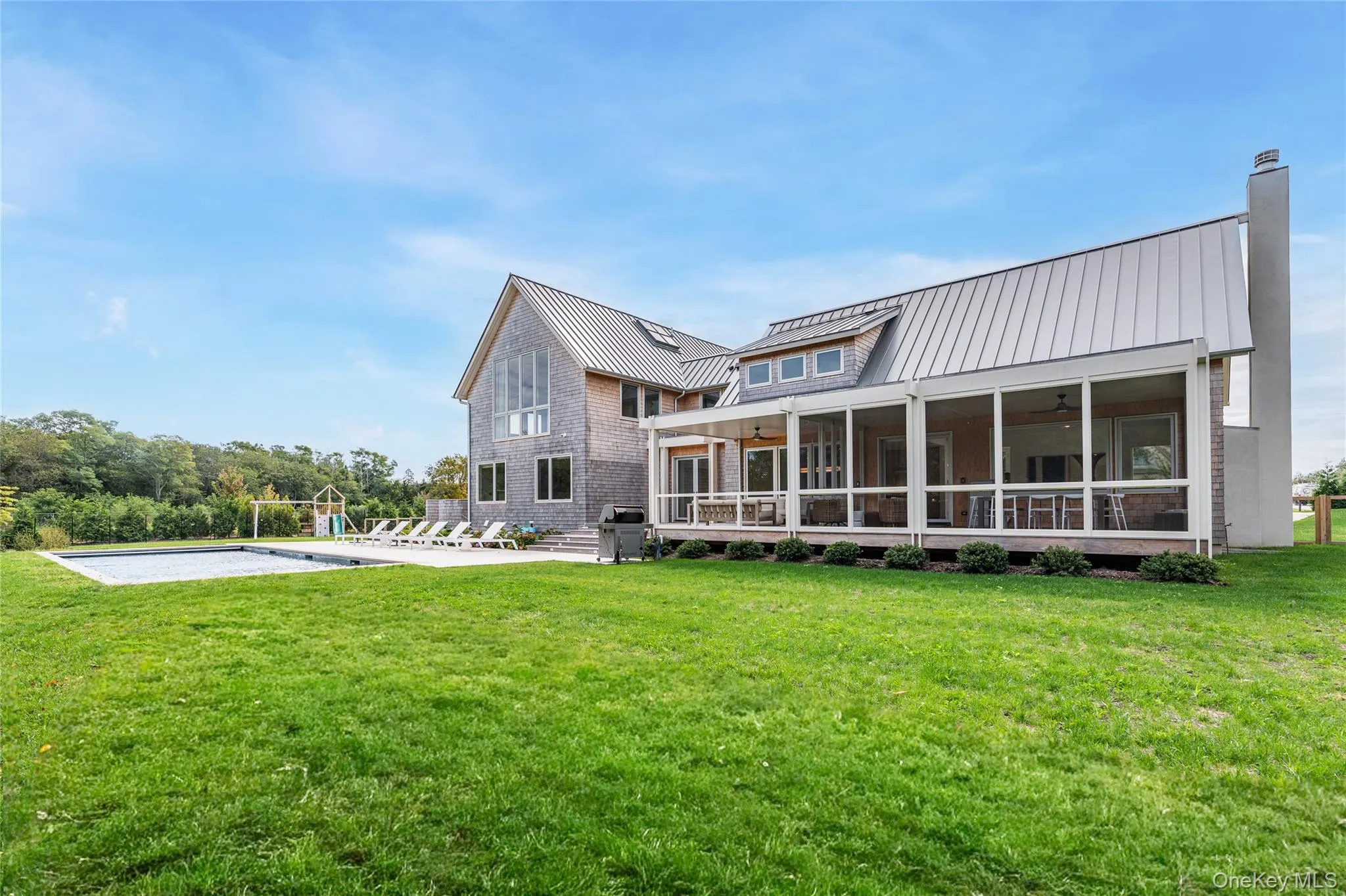 Rear view of property with a metal roof, a standing seam roof, a lawn, and ceiling fan Rear view of property with a metal roof, a standing seam roof, a lawn, and ceiling fan