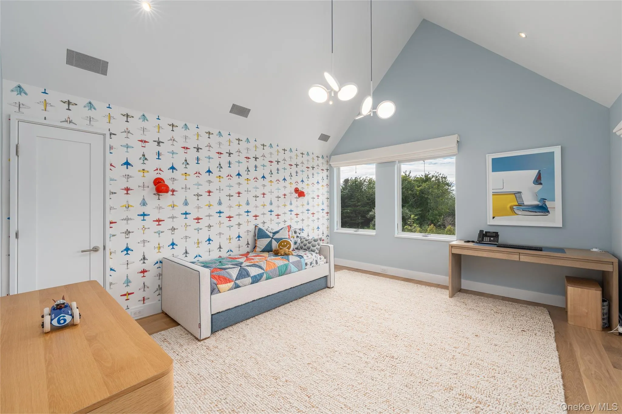 Bedroom with wallpapered walls, high vaulted ceiling, wood finished floors, and an accent wall Bedroom with wallpapered walls, high vaulted ceiling, wood finished floors, and an accent wall