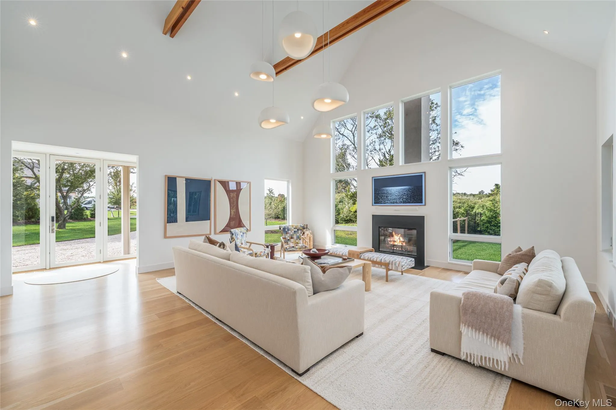 Living room with high vaulted ceiling, a glass covered fireplace, light wood-style floors, plenty of natural light, and recessed lighting Living room with high vaulted ceiling, a glass covered fireplace, light wood-style floors, plenty of natural light, and recessed lighting