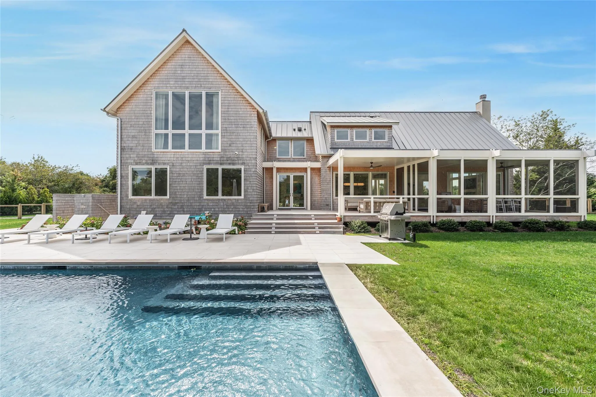 Rear view of property featuring a patio, a yard, a sunroom, and an outdoor pool Rear view of property featuring a patio, a yard, a sunroom, and an outdoor pool