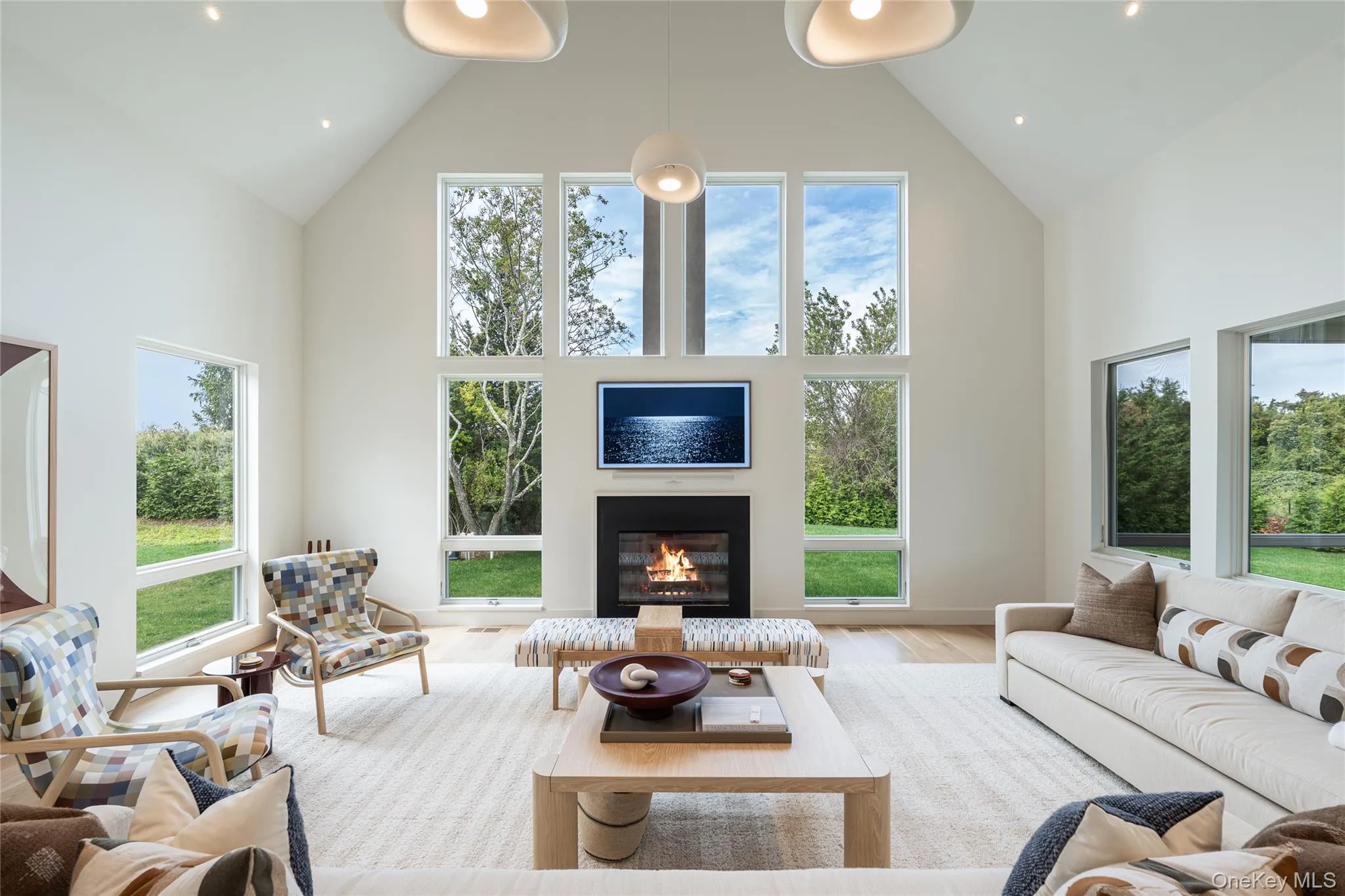 Living room featuring high vaulted ceiling, healthy amount of natural light, a glass covered fireplace, and wood finished floors Living room featuring high vaulted ceiling, healthy amount of natural light, a glass covered fireplace, and wood finished floors