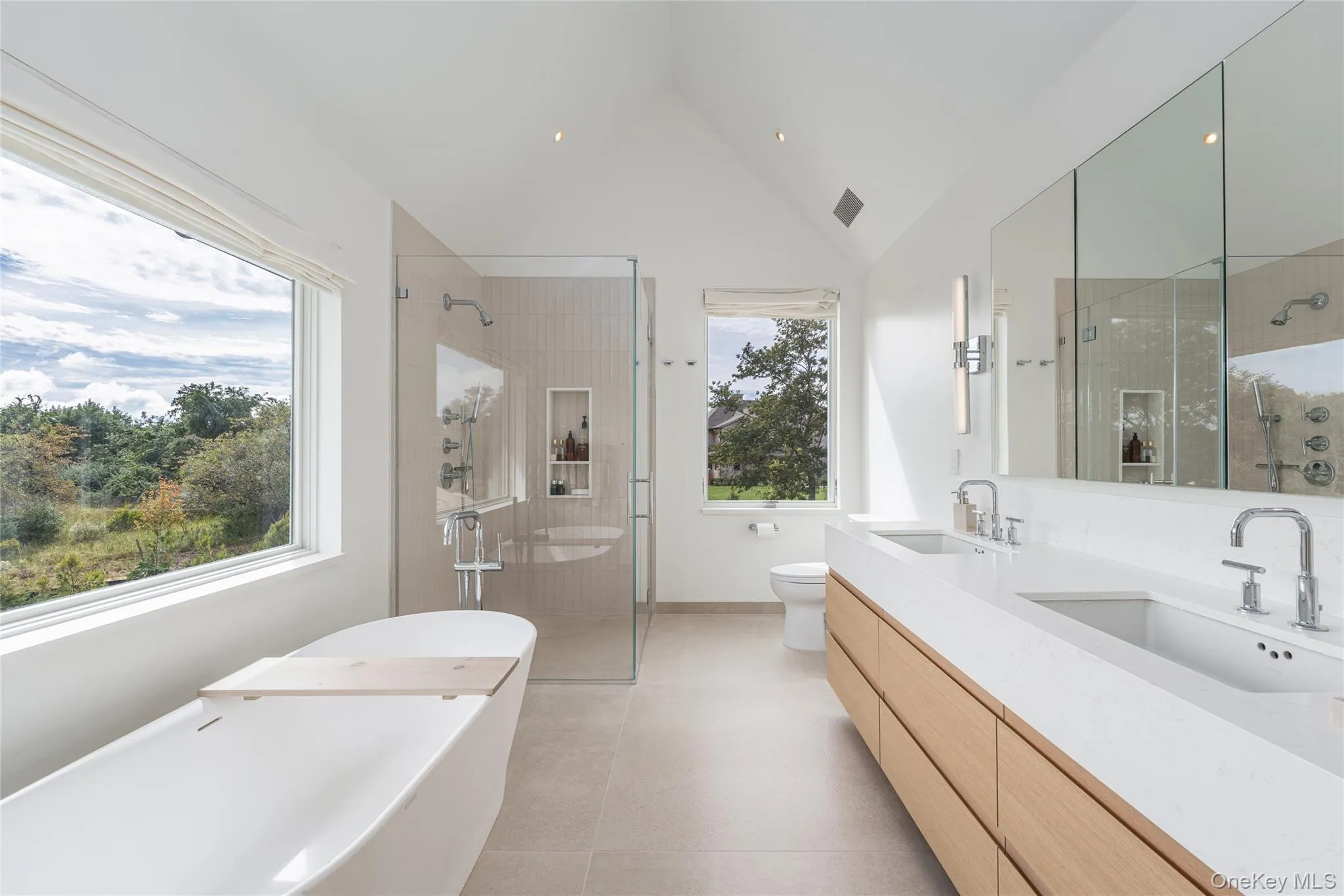 Full bathroom featuring a soaking tub, double vanity, a stall shower, vaulted ceiling, and recessed lighting Full bathroom featuring a soaking tub, double vanity, a stall shower, vaulted ceiling, and recessed lighting