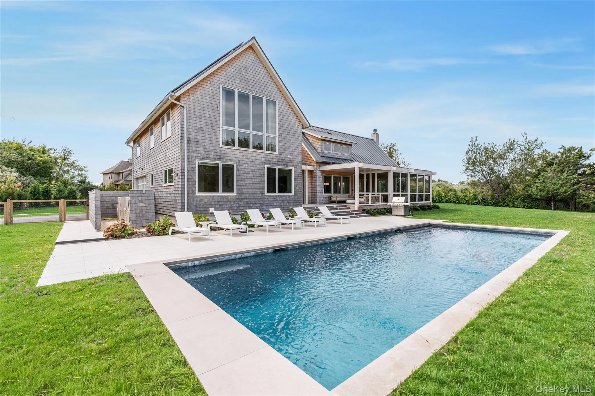 Back of house featuring a patio area, a sunroom, an outdoor pool, and a chimney Back of house featuring a patio area, a sunroom, an outdoor pool, and a chimney