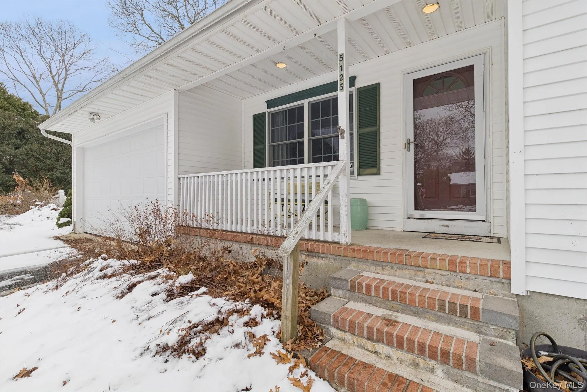 Snow covered property entrance featuring a porch and a garage Snow covered property entrance featuring a porch and a garage