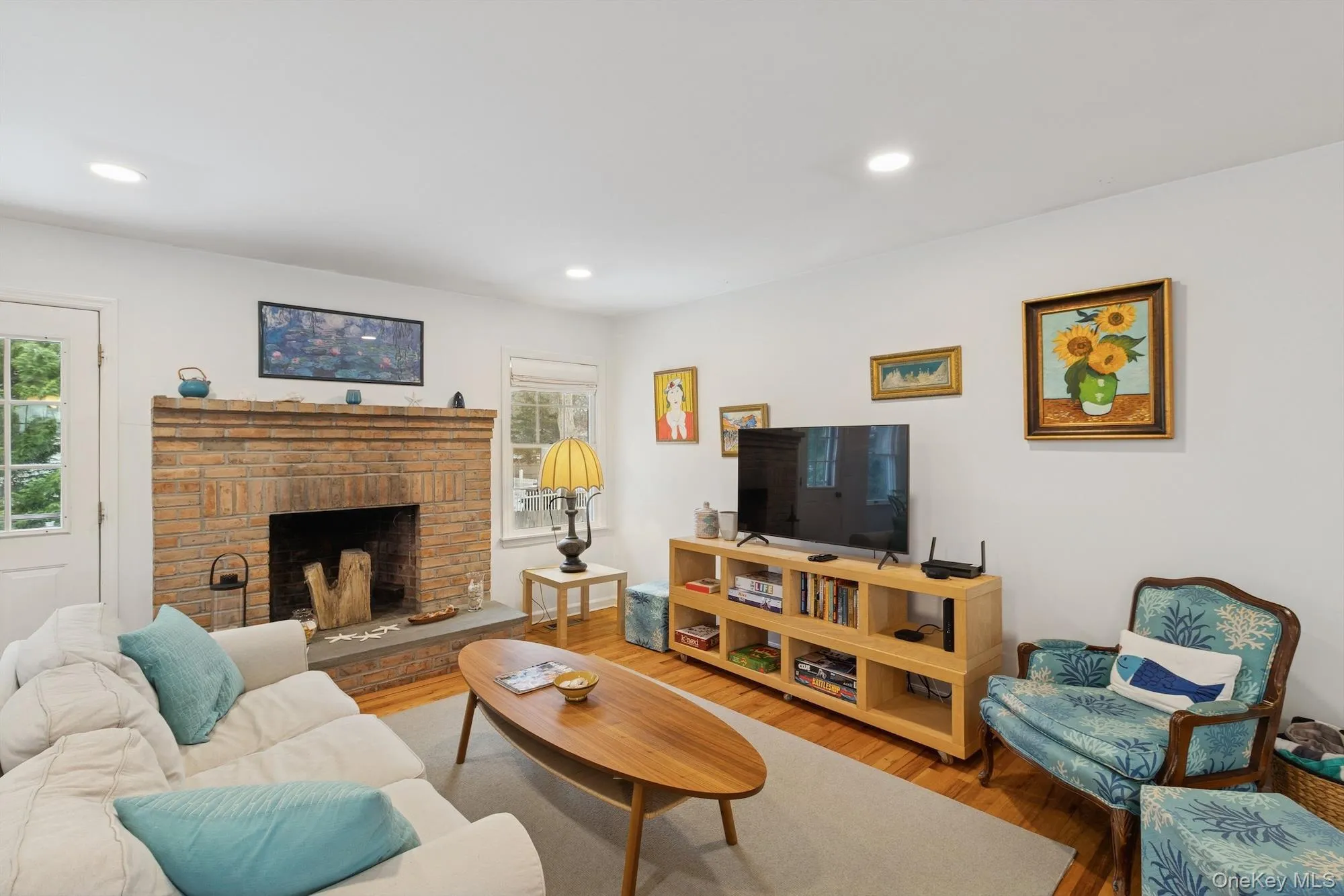 Living area with a brick fireplace, wood finished floors, and recessed lighting Living area with a brick fireplace, wood finished floors, and recessed lighting