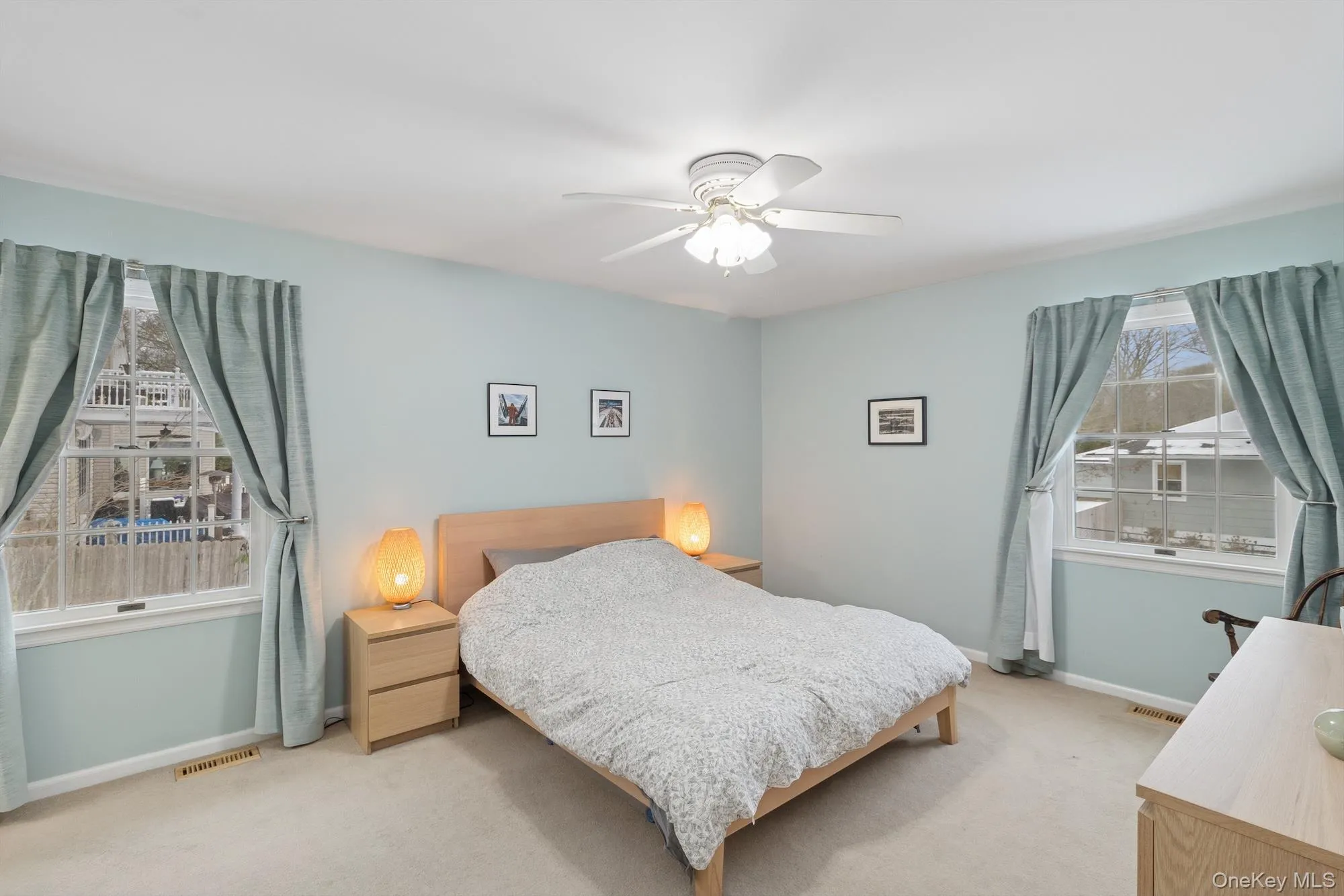 Carpeted bedroom featuring multiple windows and a ceiling fan Carpeted bedroom featuring multiple windows and a ceiling fan