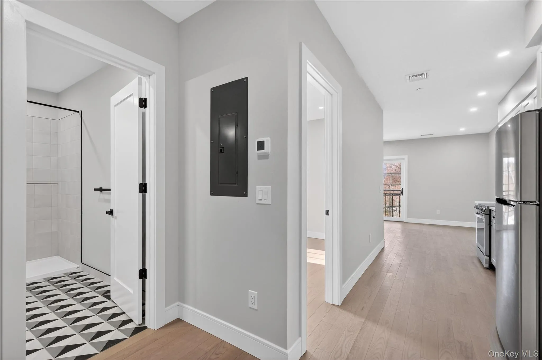 Hallway with light wood-style floors, electric panel, and recessed lighting Hallway with light wood-style floors, electric panel, and recessed lighting
